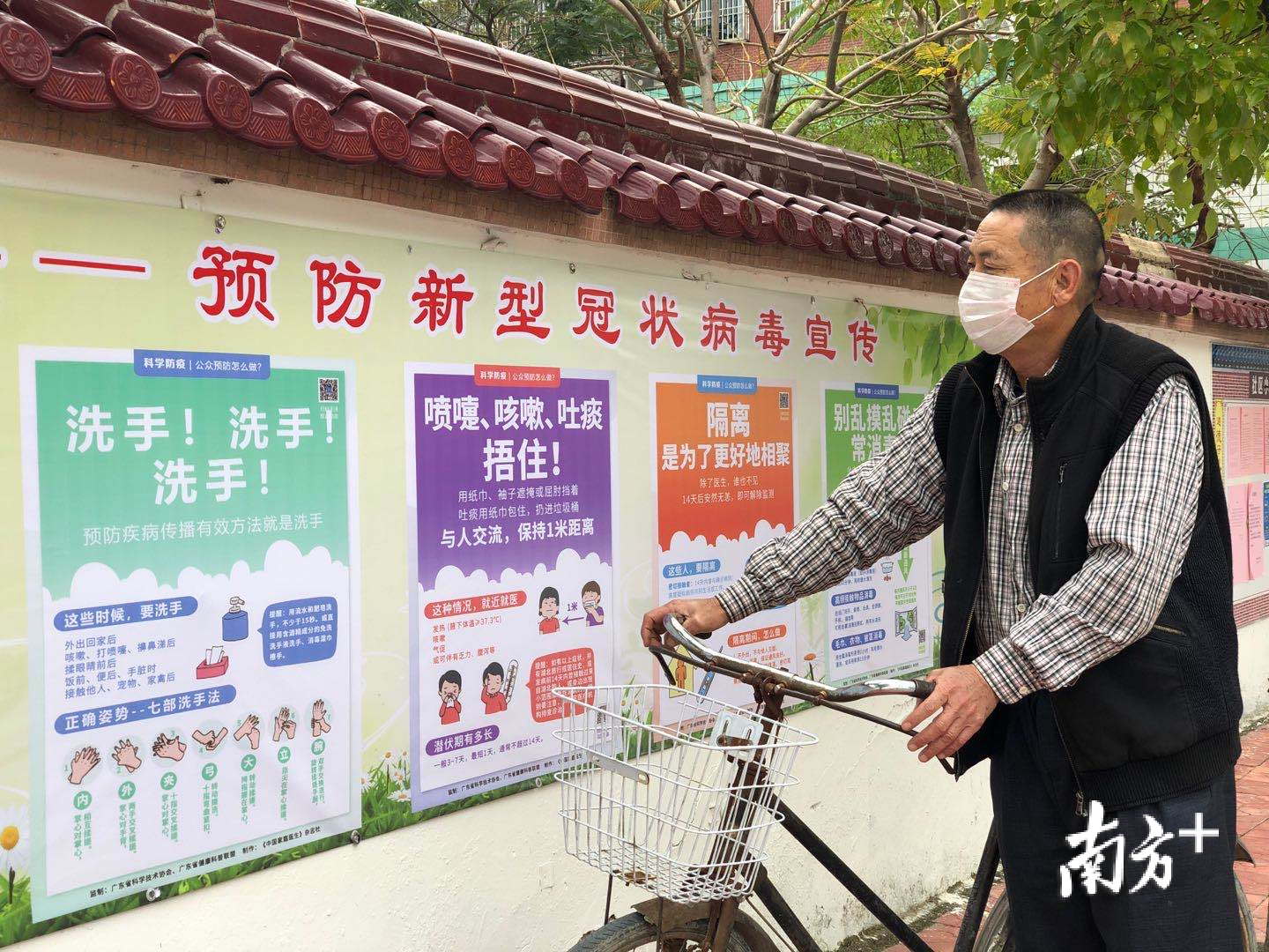 村民观看社区张贴的防疫宣传画。余丹 摄