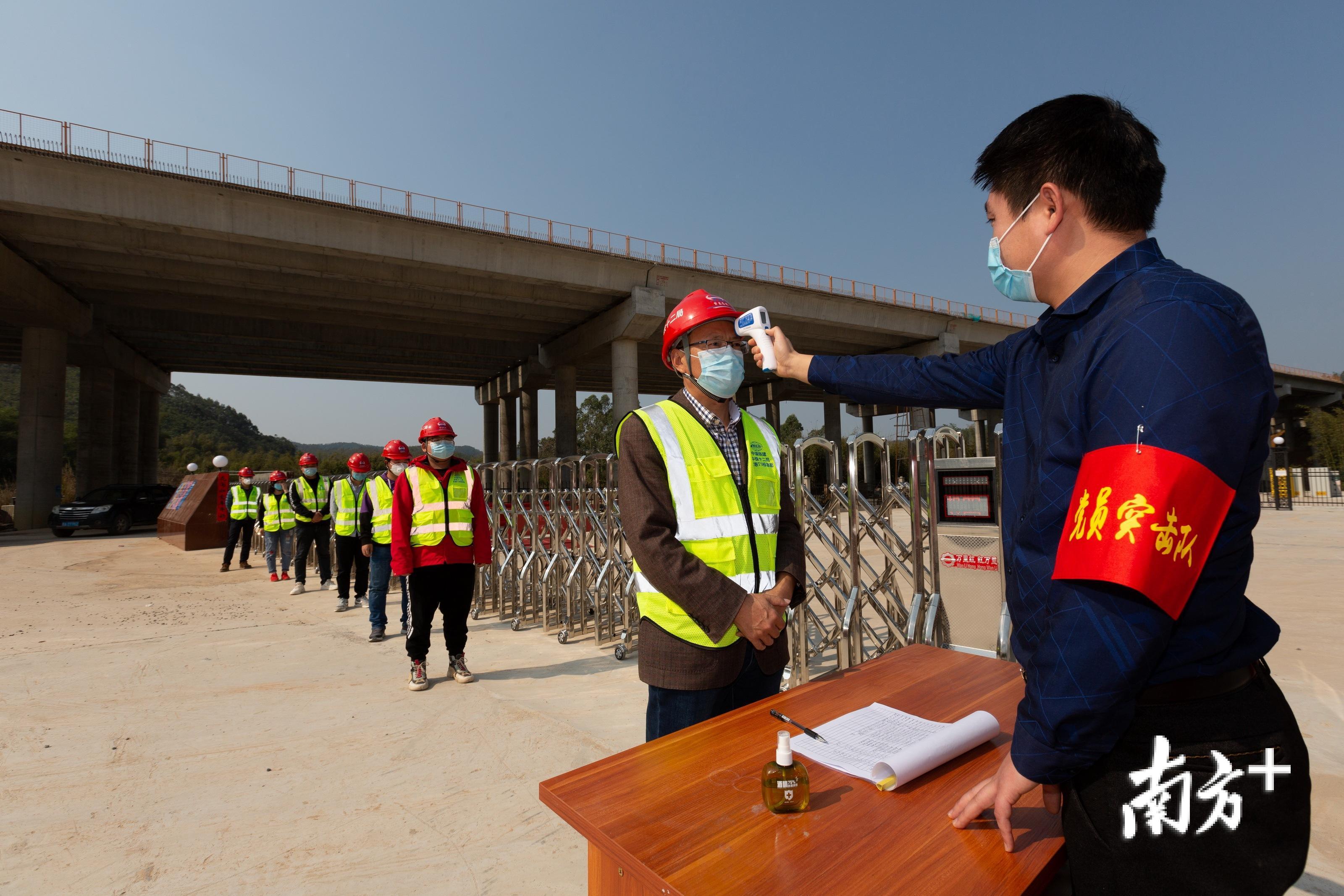 工人依次接受体温检测等三道关卡。