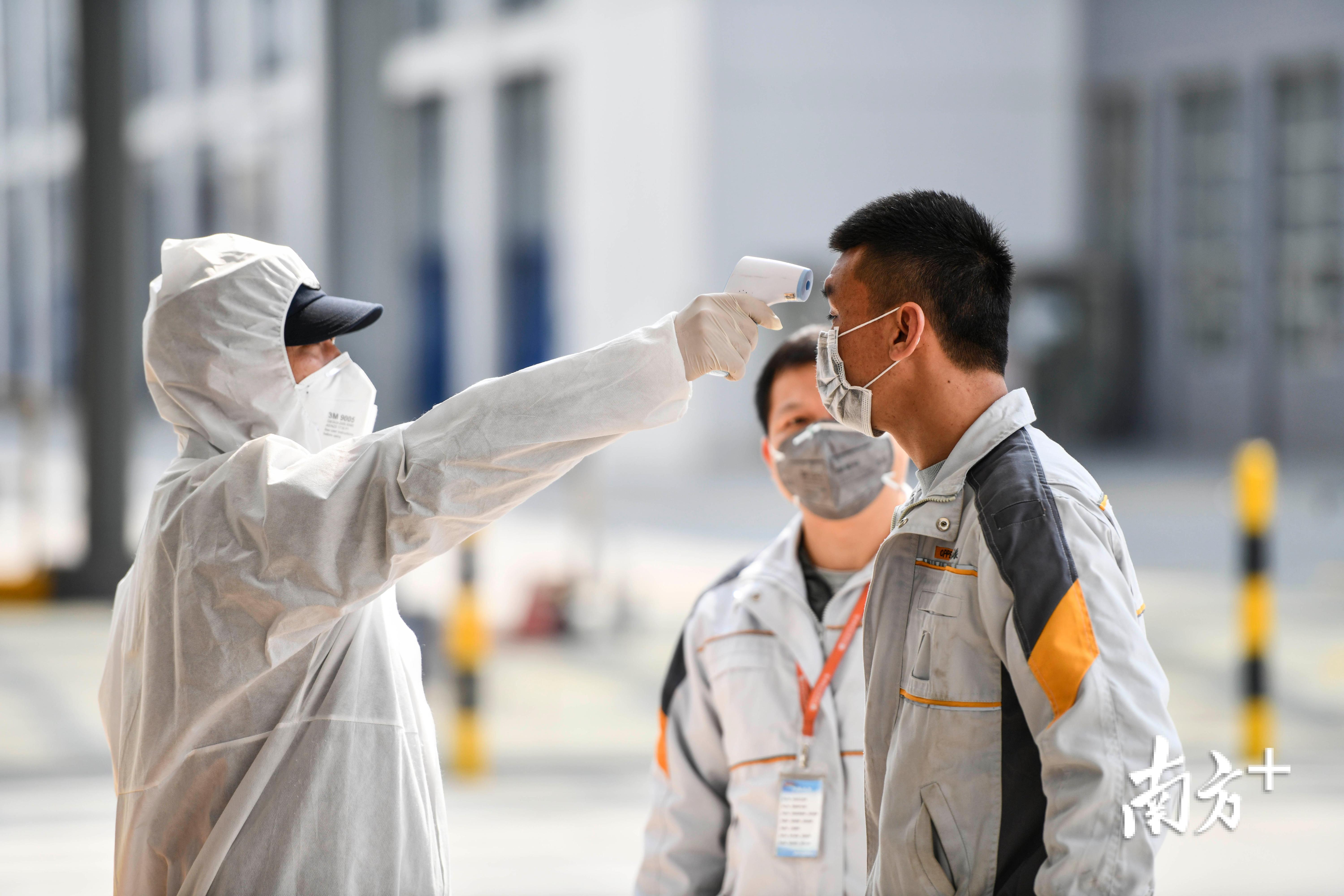 欧派清远项目门口,安保人员对出入工人进行体温检测.