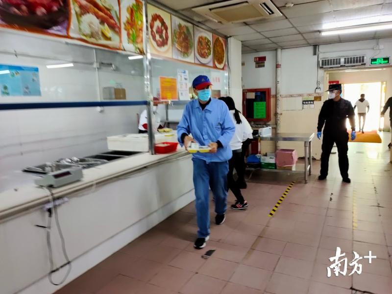 员工快速取餐，即拿即走，旁边有安保人员进行监督。