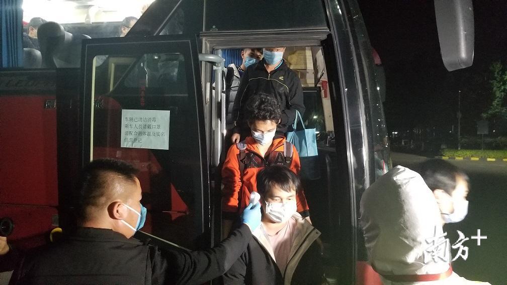 刚刚下车的返岗员工正在接受体温测量。羊建溶摄