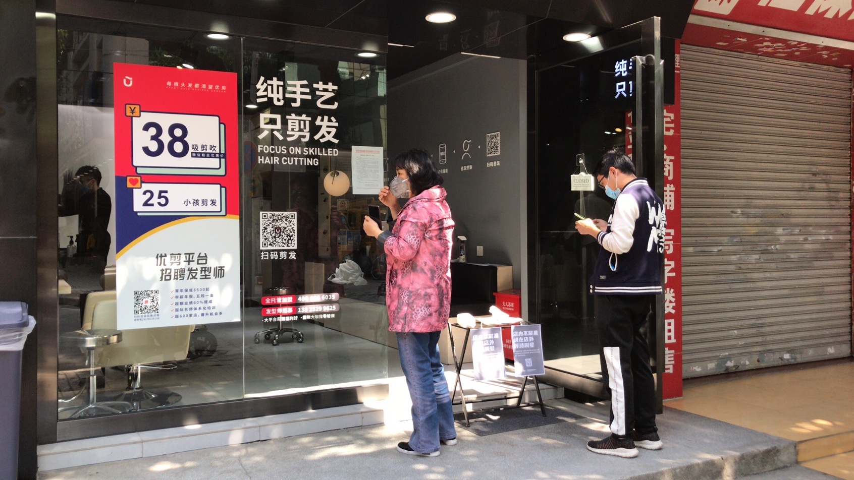 记者到访东兴南路一家理发店,发现店铺外陆续有顾客,扫码排队理发