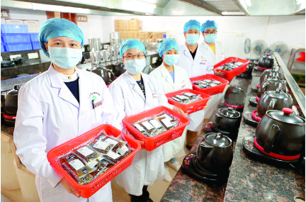 药剂师展示煎煮好的中药汤剂产品。惠州日报记者李松权 通讯员李连君 摄