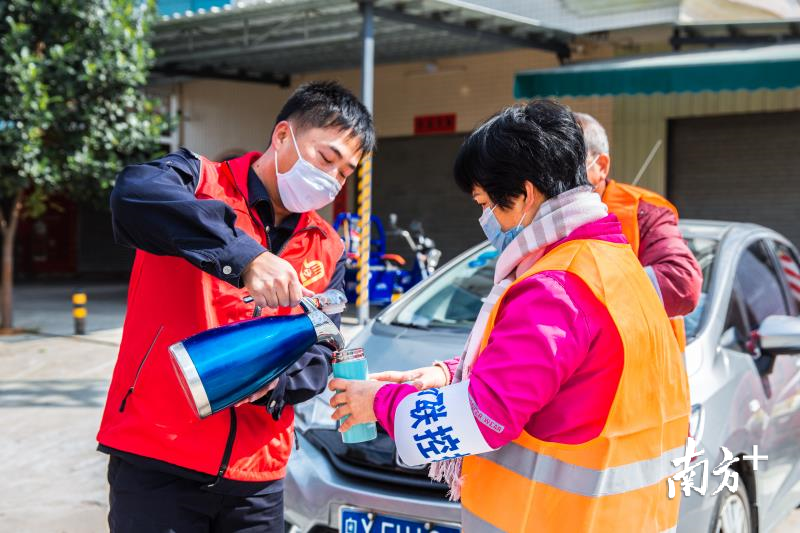 身穿红马甲，党员志愿者为社区工作人员送上热茶水。通讯员供图
