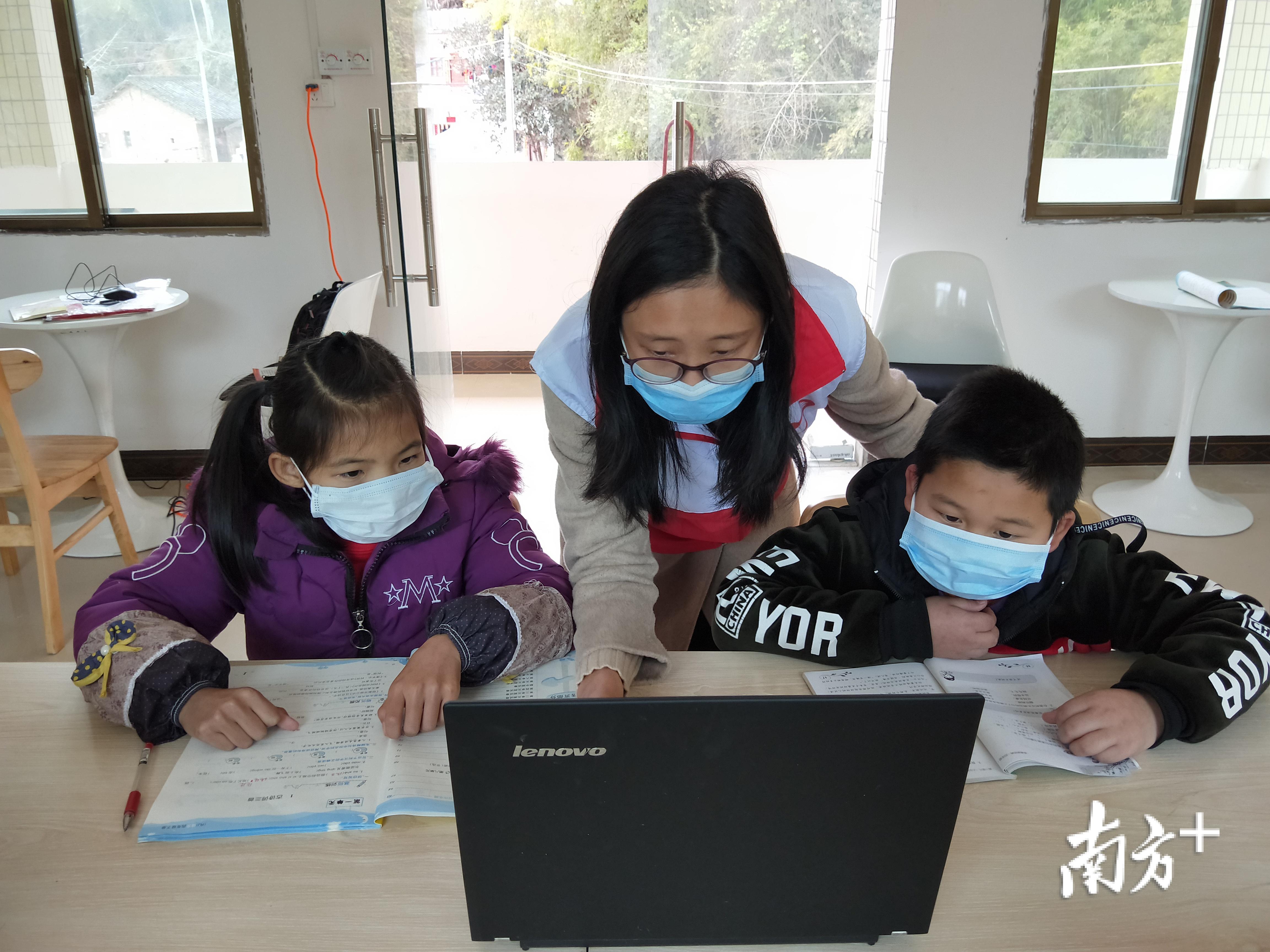 韶关南雄市南亩镇中寺村驻村干部黄莉和赵园园在“特殊课堂”为孩子辅导功课。通讯员供图