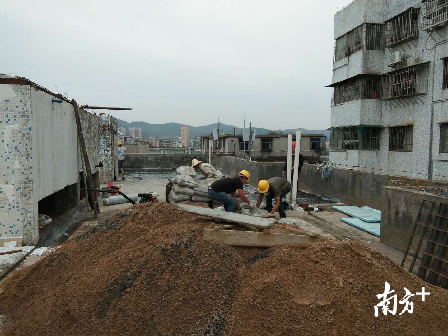 工人正在给省五建四工区宿舍楼顶做防水隔热。