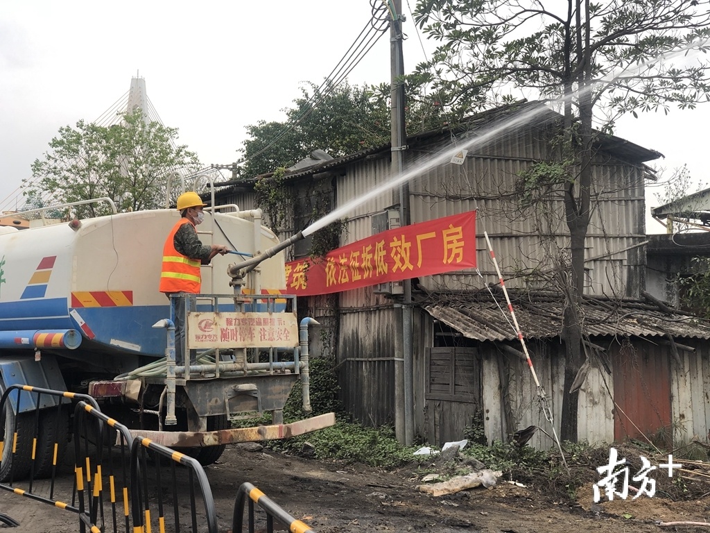 工作人员对拆除墙体喷水，以抑制扬尘的产生。余丹摄