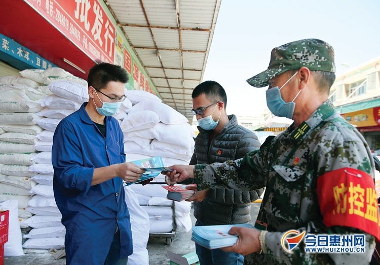 物流园工作人员给商户派发资料，宣传防疫注意事项。
