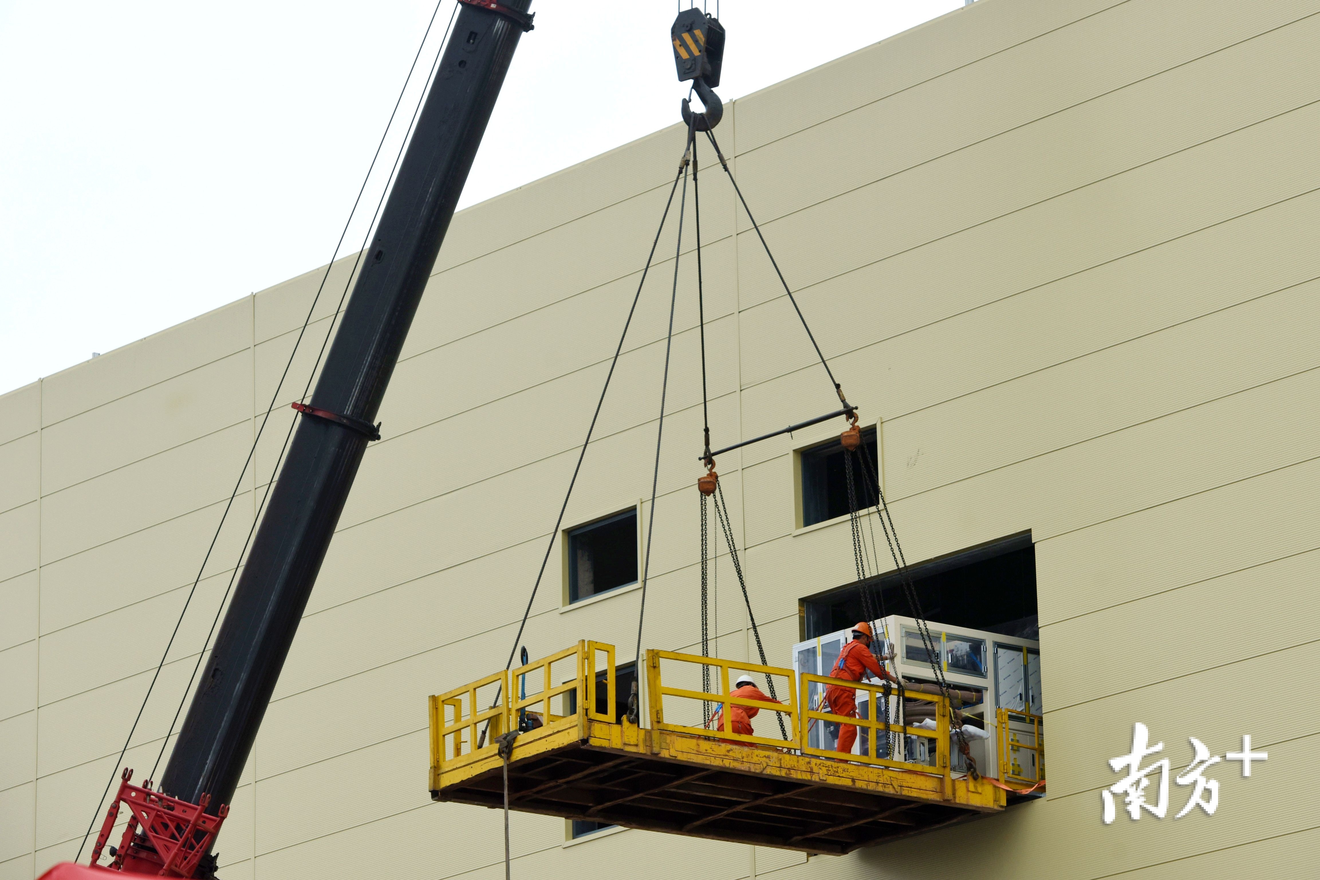 工人将生产设备运进惠州亿纬汽车用软包叠片电池项目三期建设厂房里。 工人将生产设备运进惠州亿纬汽车用软包叠片电池项目三期建设厂房里。