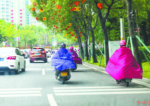 下雨天，骑乘摩托车的市民大多穿上连体雨衣。梁文栋 摄