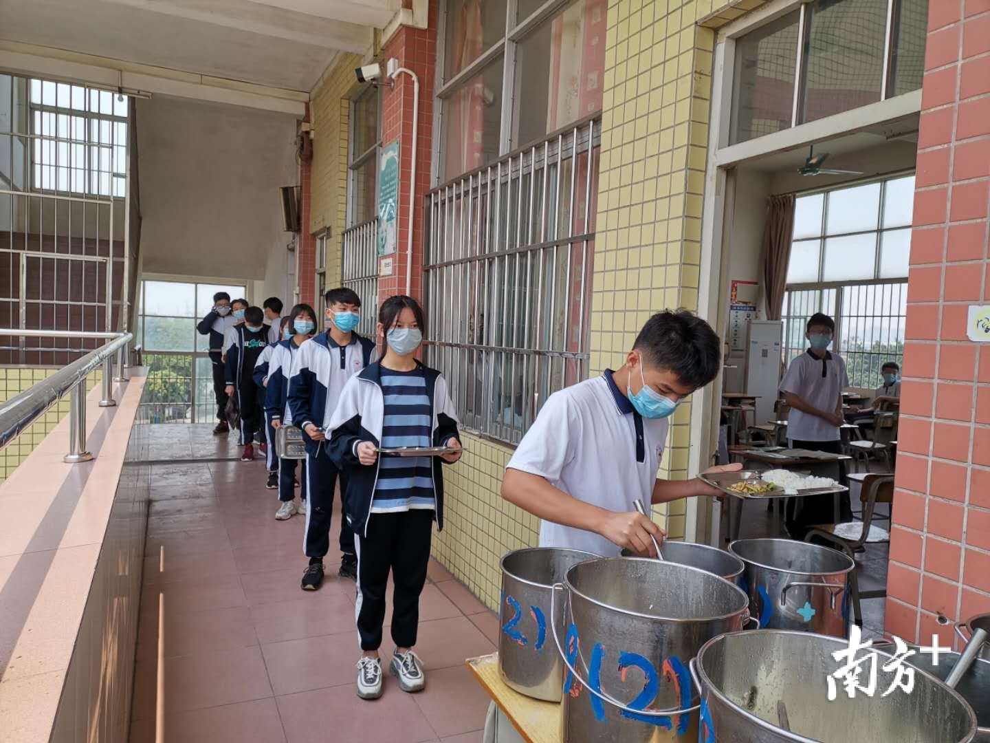 江海区阳光学校学生间隔1米排队领餐。