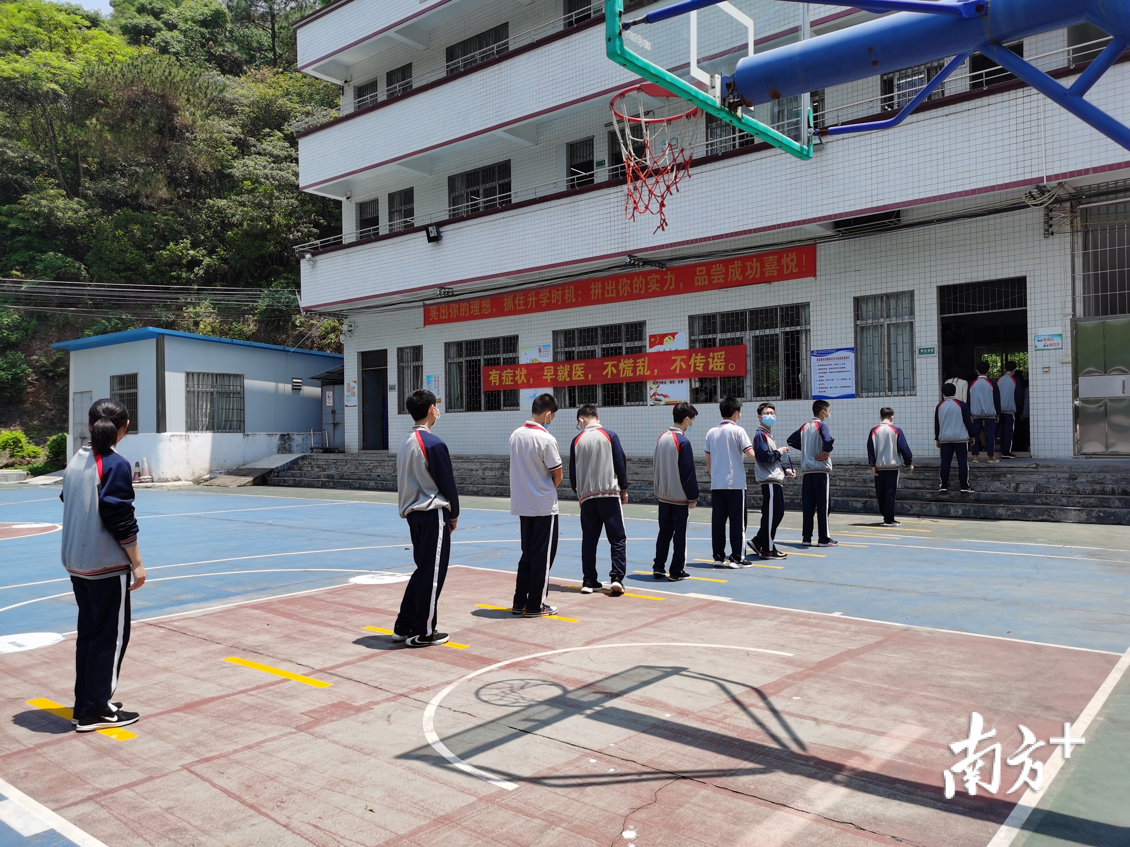 蓬江区棠下镇虎岭初中学生在饭堂外，间隔1米以上排队领餐。
