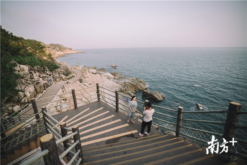 游客在海龟湾滨海栈道上拍照留念。