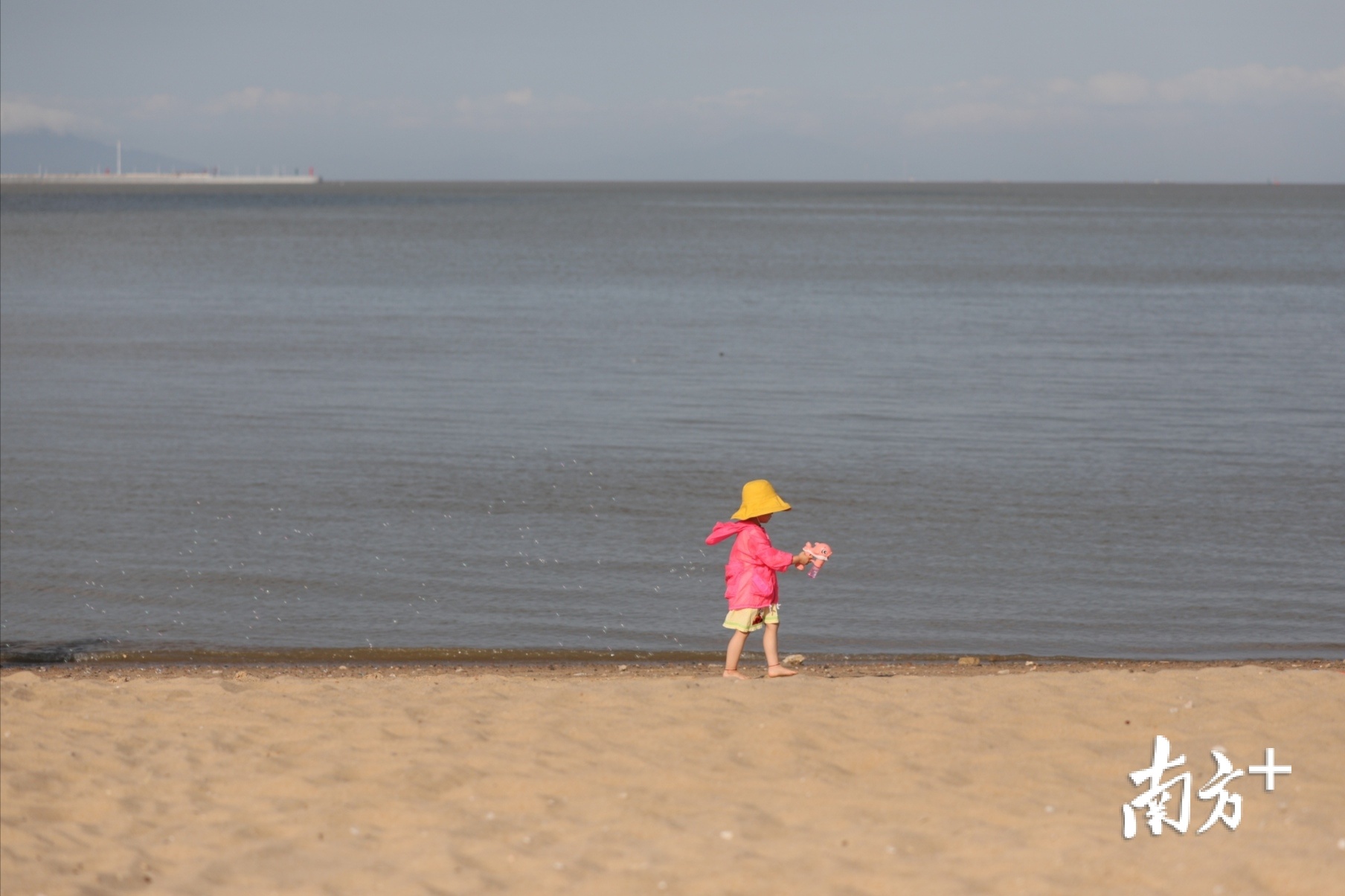 一名小女孩在海边玩着泡泡