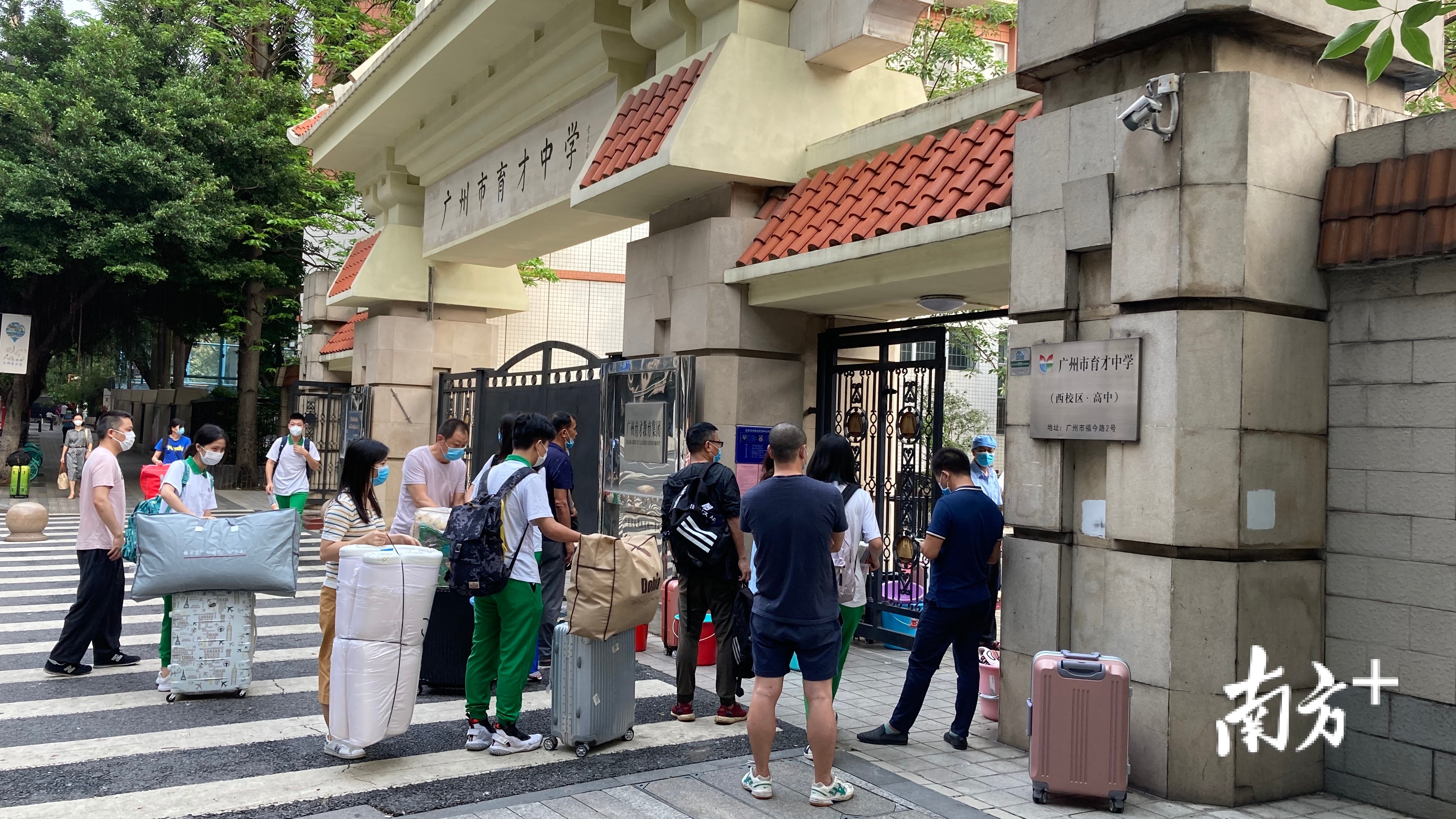 学生与家长拎着行李进校。