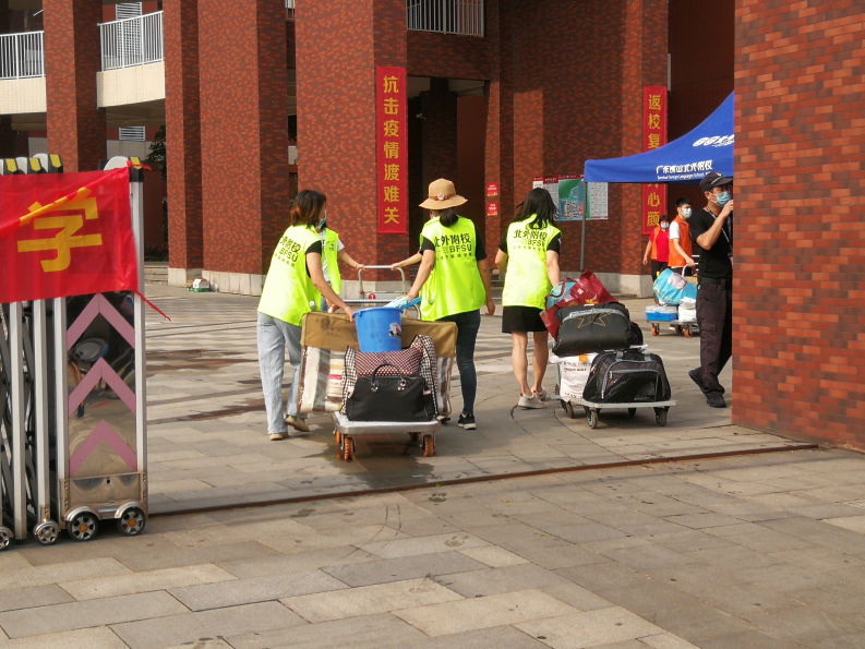 三水区各校教职工纷纷变身“志愿队”,在校门口帮助学生搬运行李。