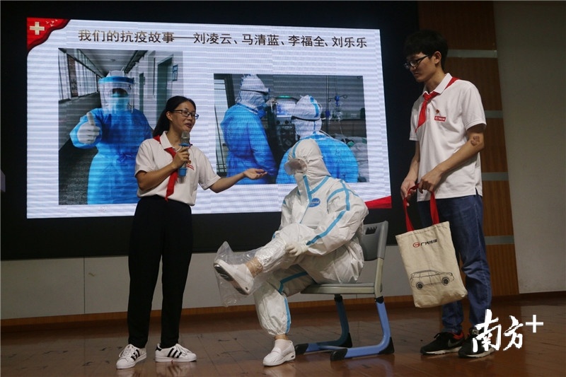江门市中心医院抗疫医疗队员代表刘乐乐（左二）在马清蓝（左一）、李福全（左二）的协助下，演示穿防护服的全套流程。