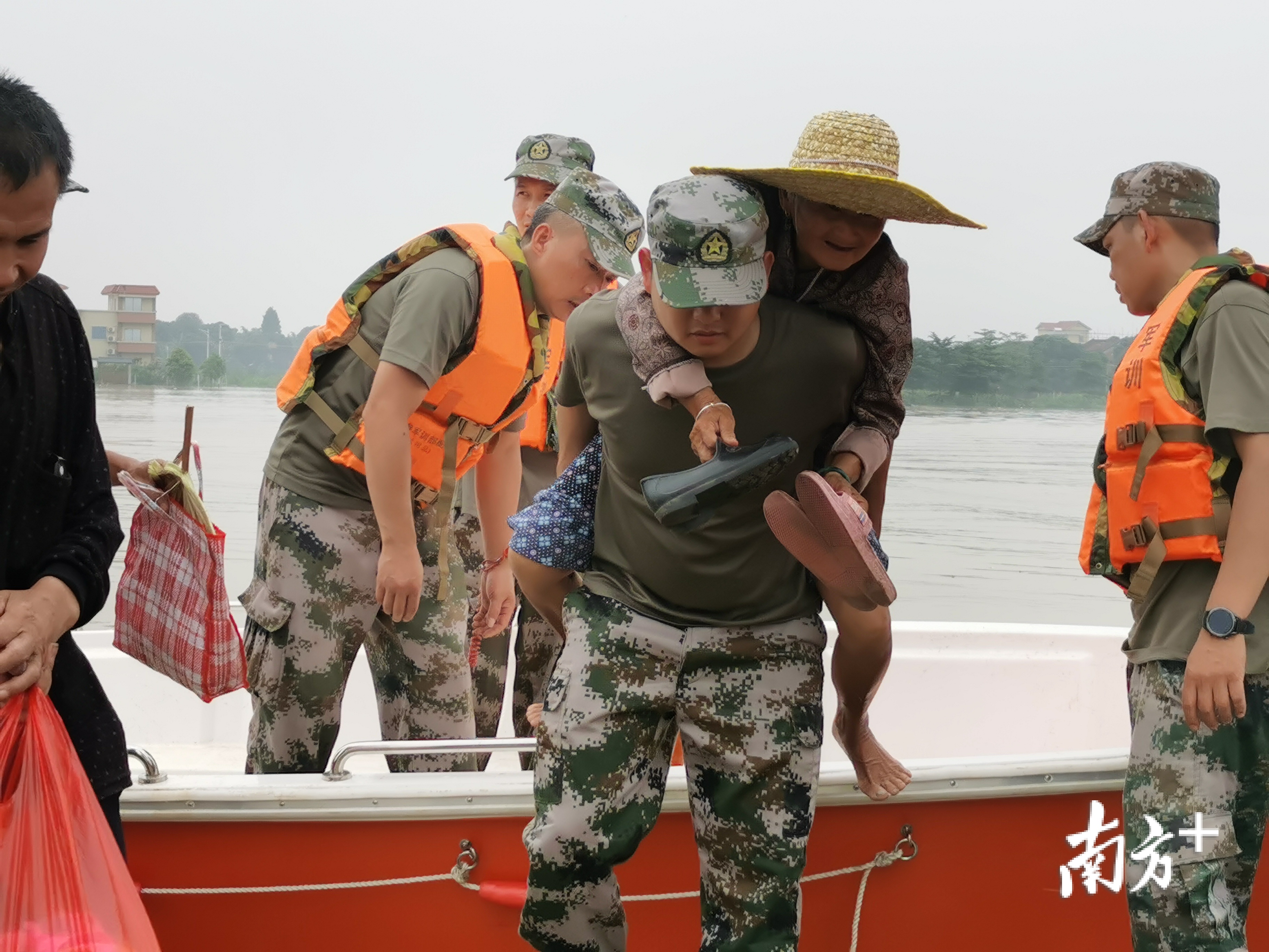 民兵队员背着老年群众转移。