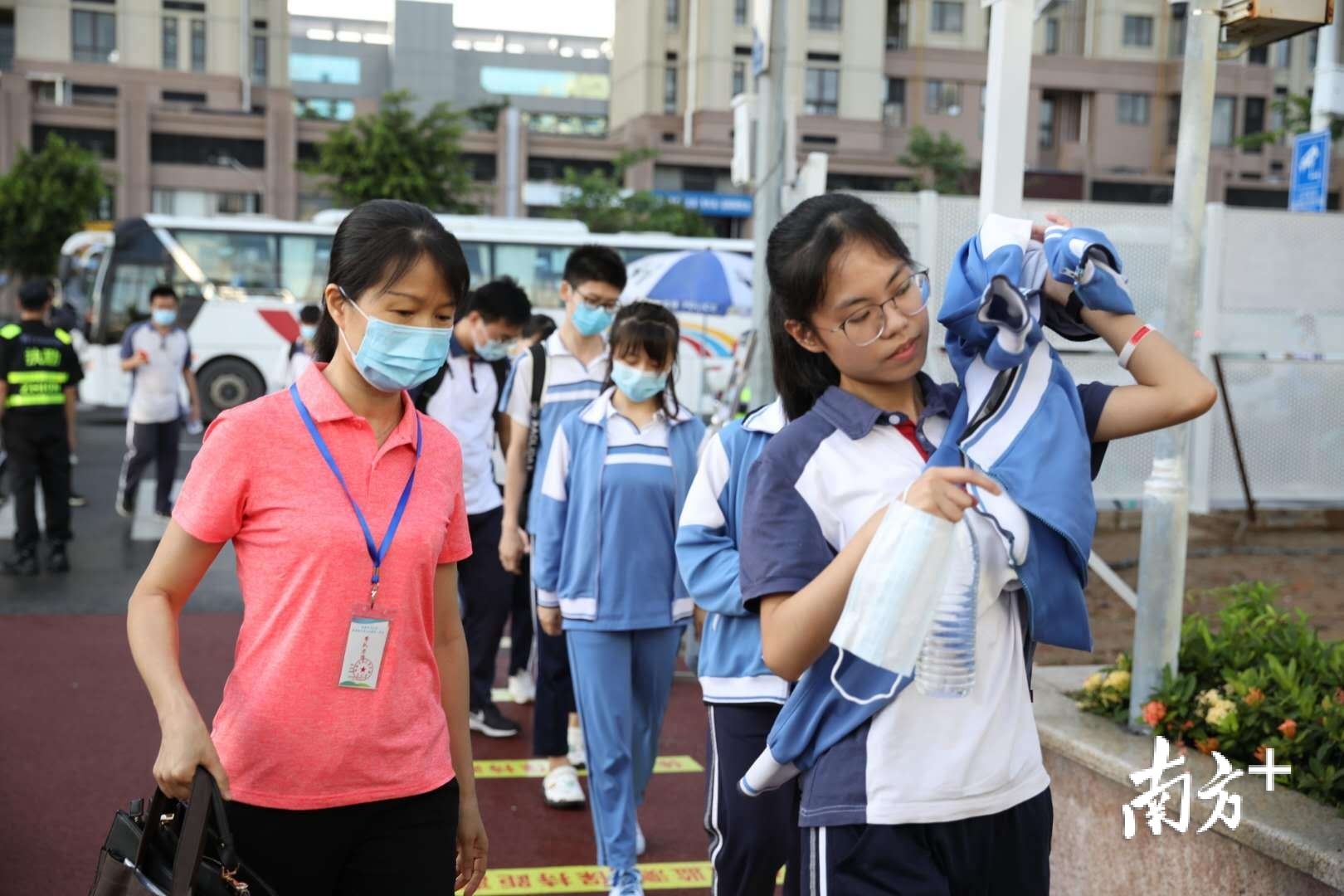 特意身穿红色衣服的老师送学生进入考场,嘱咐着学生考试注意事项