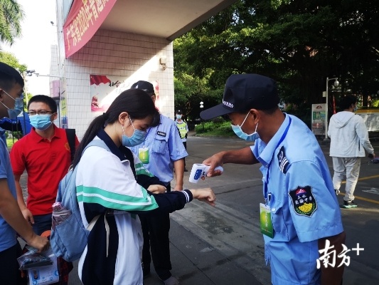 在三水区实验中学考点,校卫人员为考生检查证件、测量体温。李周秦 摄 在三水区实验中学考点,校卫人员为考生检查证件、测量体温。李周秦 摄