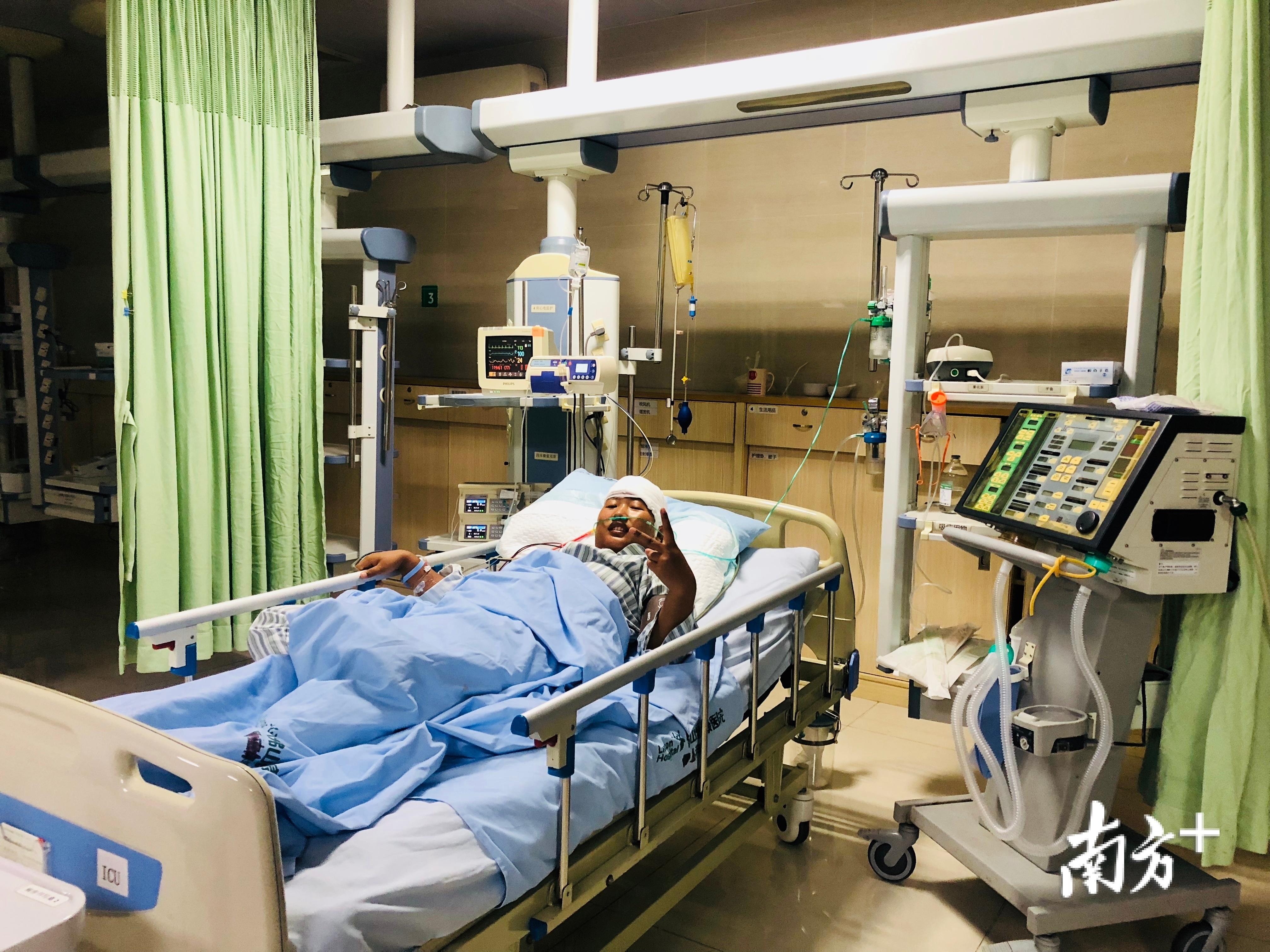 术后第一天，魏月董在ICU，意识已清醒，并对镜头做出胜利手势。 佛山岭南医院供图