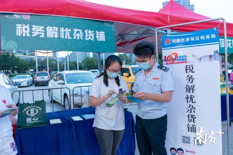 图为源城区税务人员在河源2020年首届文旅繁华音乐季活动现场开设“税务解忧杂货铺”，向周边店主及过往市民宣传讲解相关税费优惠政策。蓝天红 摄