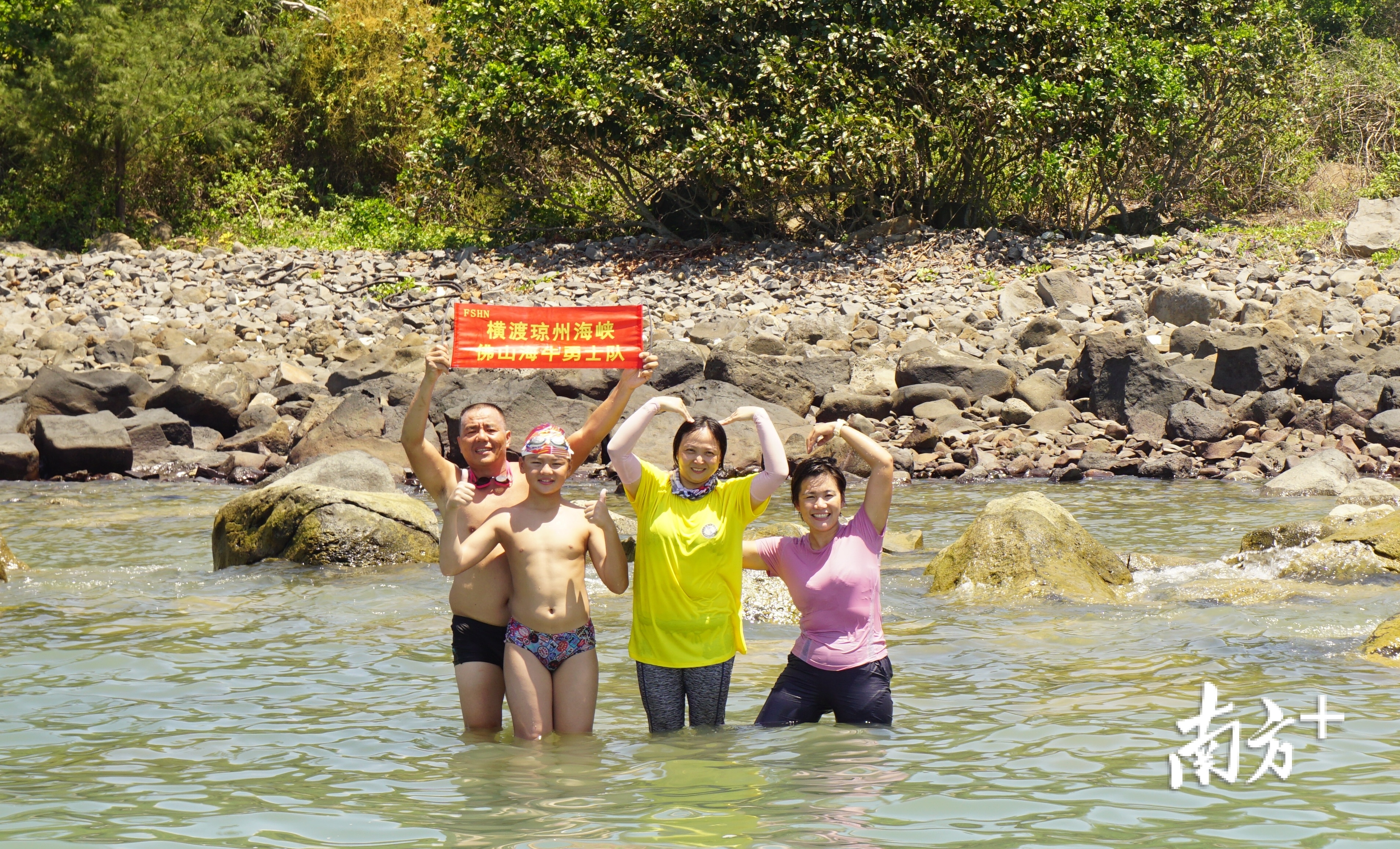 横渡成功后，刘柏言母亲（右2）与啦啦队跳下海里与刘柏言合影。受访者供图