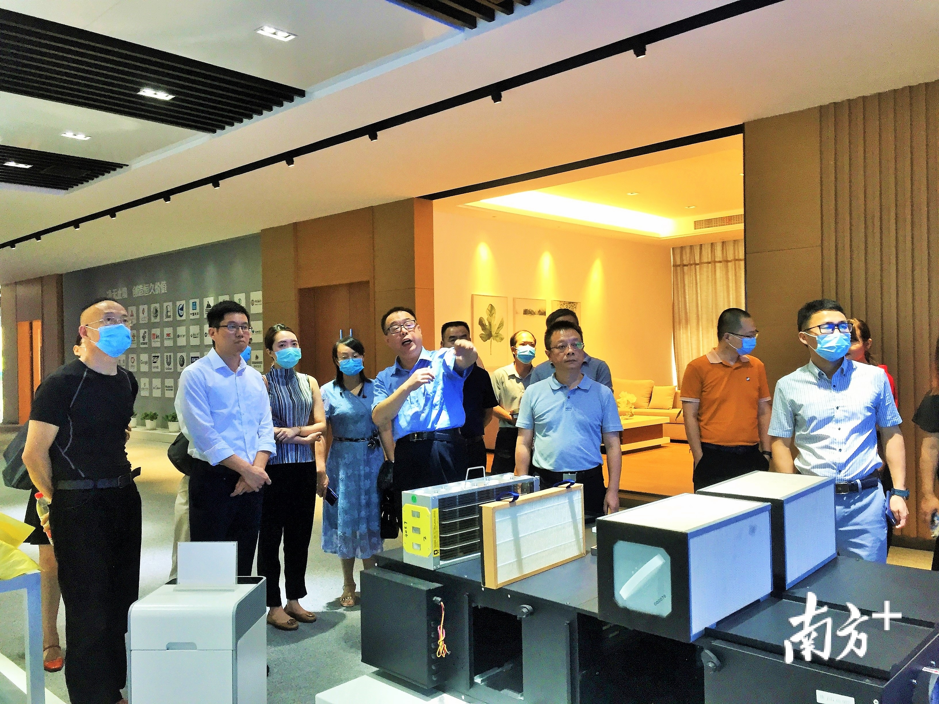 宾肯电气总经理王飞（中）向顺德高质量发展对标考察团介绍公司地铁站厅吊装式空气消毒方案。欧阳少伟 摄