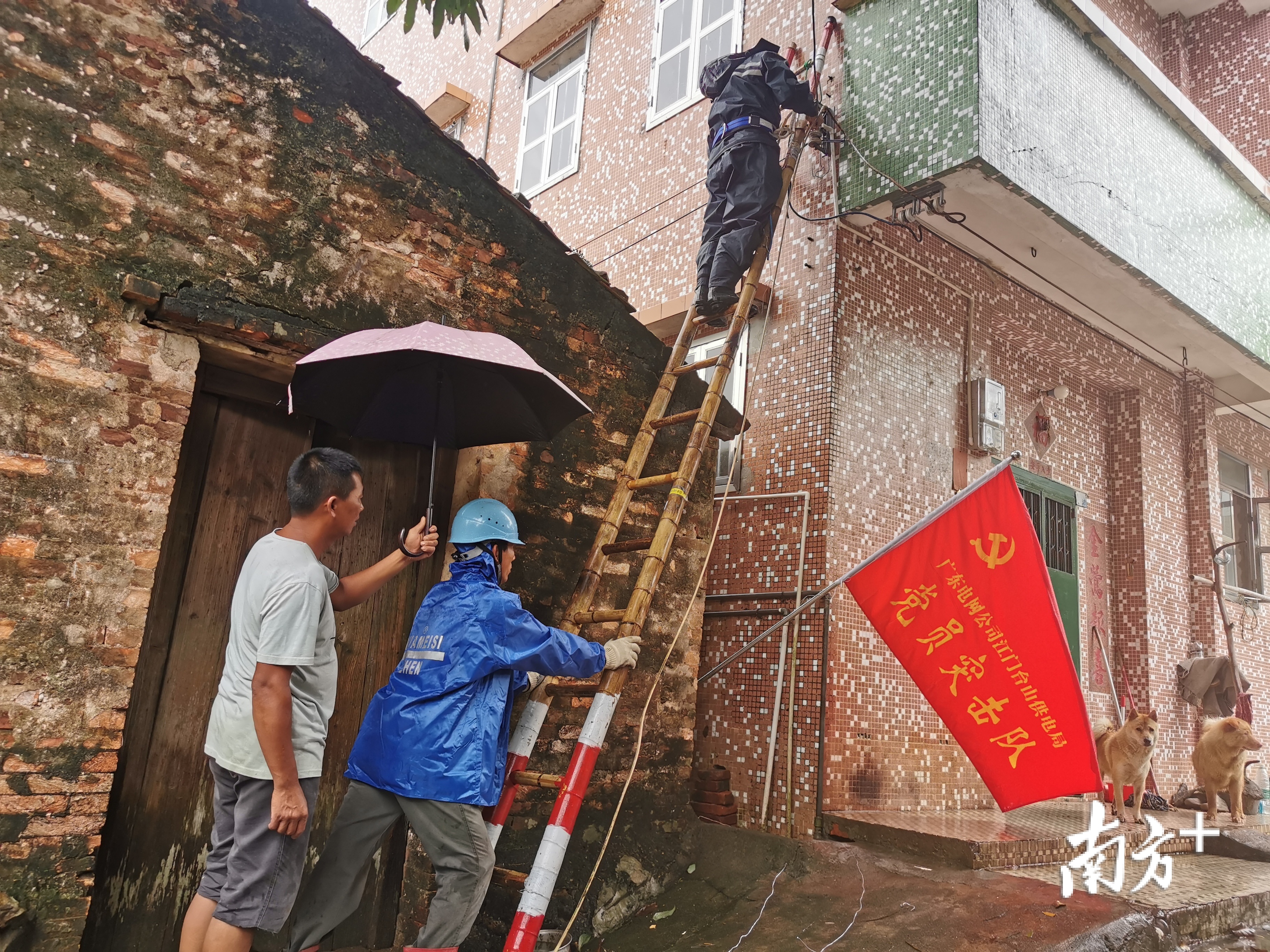 台风“海高斯”过境江门，南方电网广东江门台山供电局三合供电所工作人员对新三八佛凹村抢修。抢修过程中突然下起雨，村民为抢修人员撑起了“爱心伞”。莫靖聪 摄