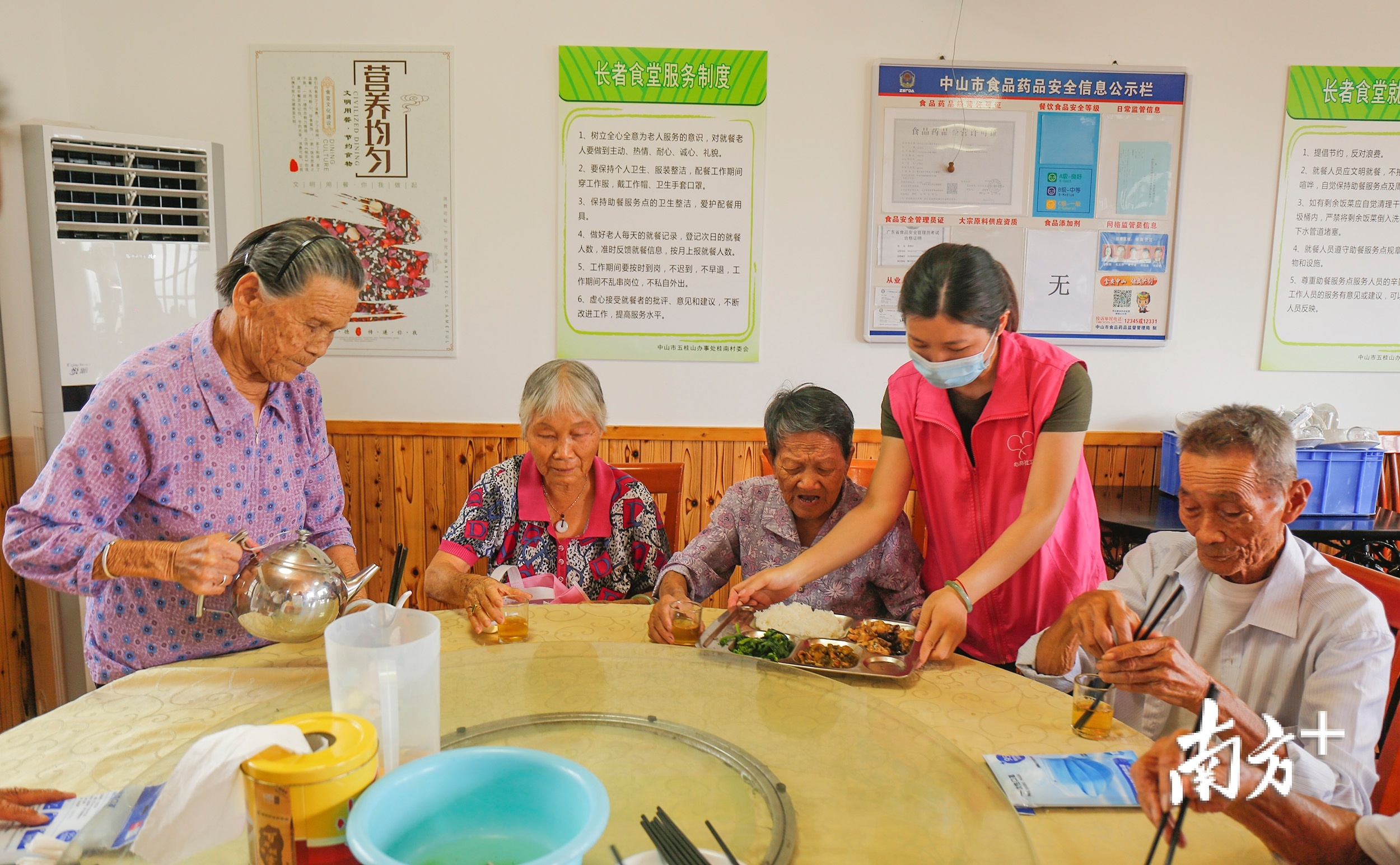 在桂南村长者食堂内，四十余名老人在工作人员的带领下有序登记、测温、就餐。