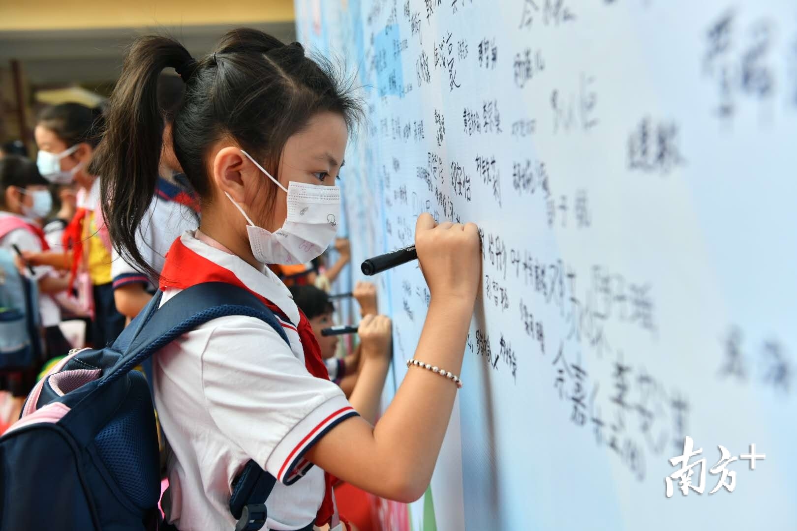 开学第一天，玫瑰小学的孩子们在“创文”签名板上写下自己的名字。南方日报记者 戴嘉信 摄
