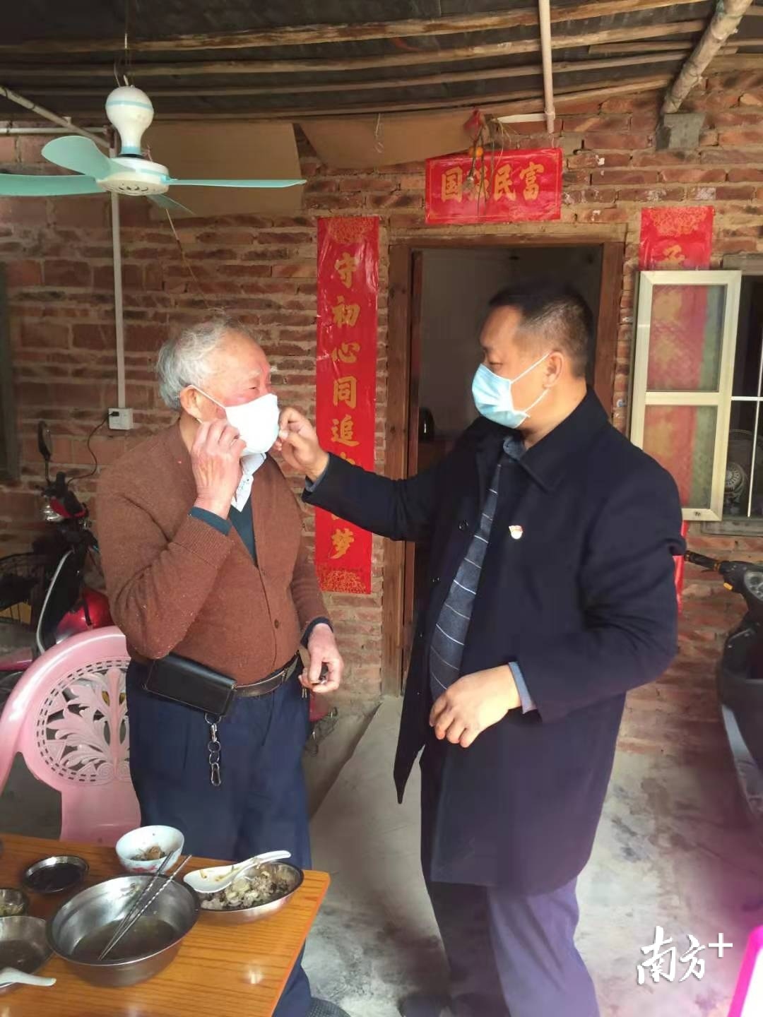 潘玉恒(右)指导村民口罩佩戴方法和宣传防疫知识。许松波 摄 潘玉恒(右)指导村民口罩佩戴方法和宣传防疫知识。许松波 摄