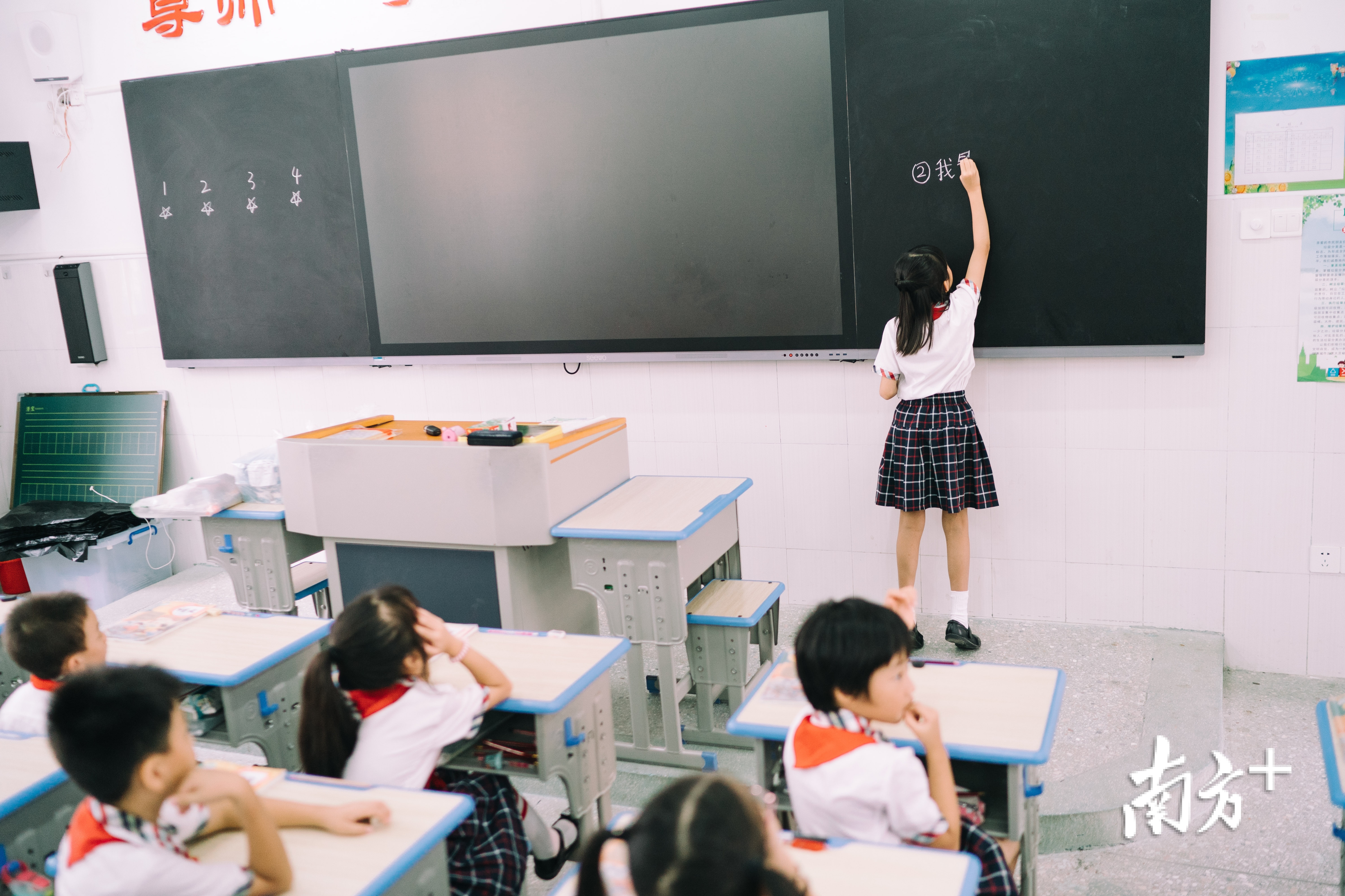 黄玥然垫着脚在黑板上写下课文名称。