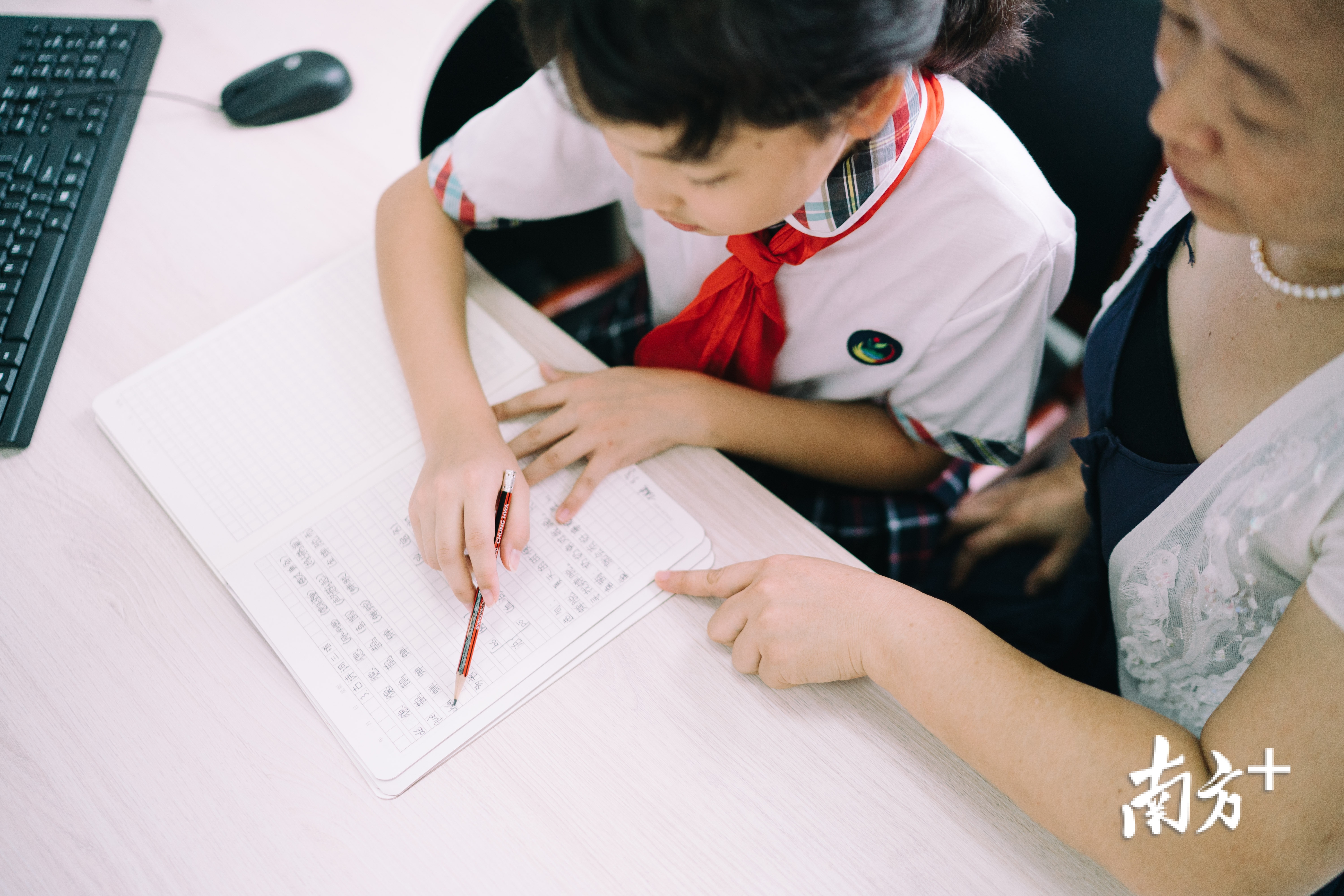 黄梓涵在老师的陪同下批改作业。