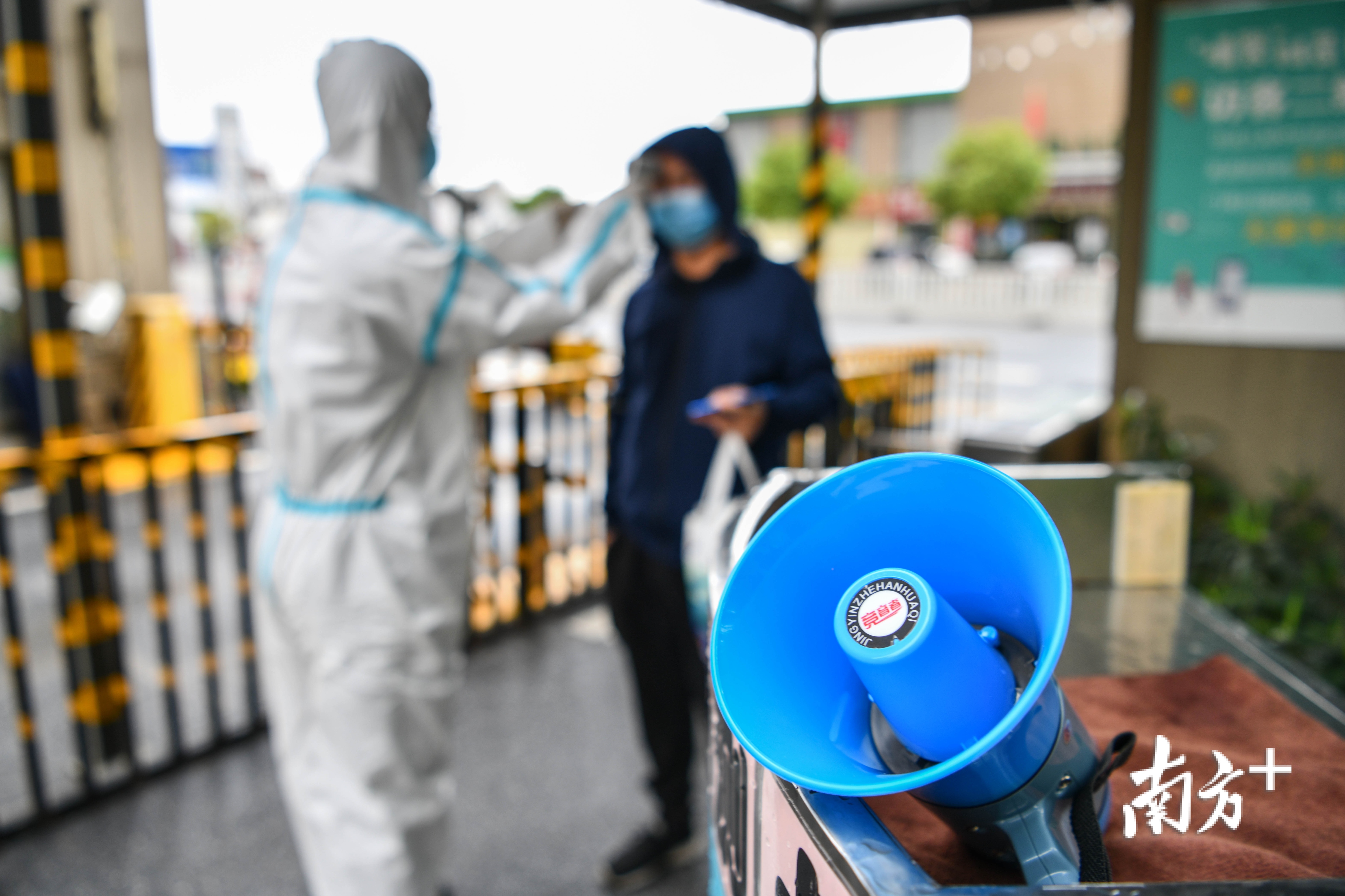 清远市，身穿防护衣的物业工作人员对进入小区人员进行体温检测。 记者 曾亮超 摄