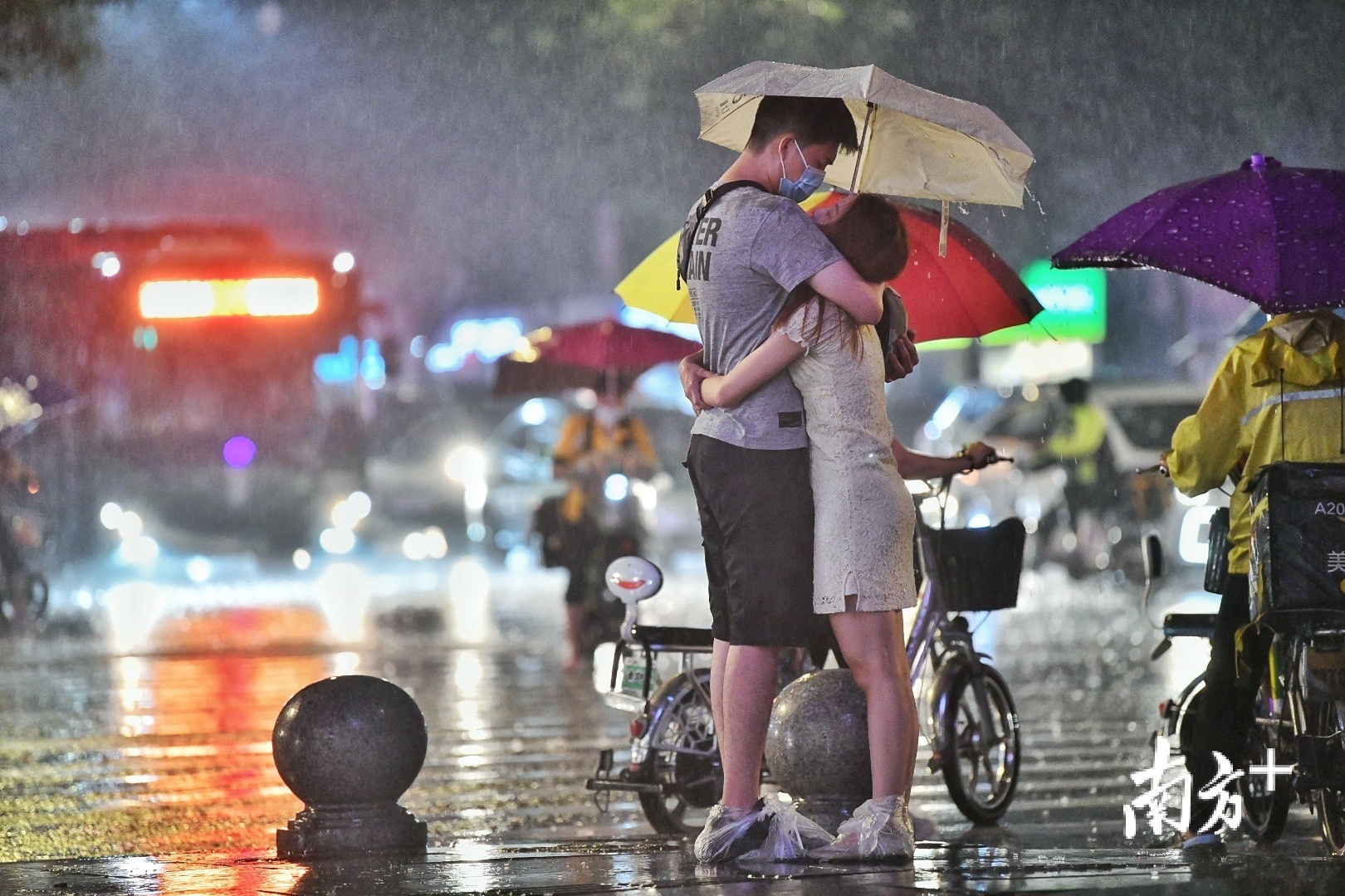 江南大道中,一对情侣在风雨中紧紧依偎在一起