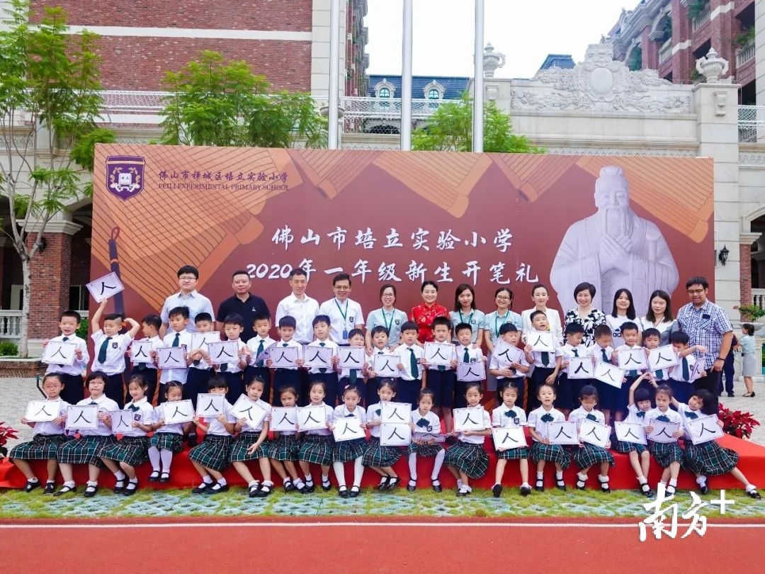 一年级新生手举“人”字和校长、老师们合影。通讯员供图 一年级新生手举“人”字和校长、老师们合影。通讯员供图