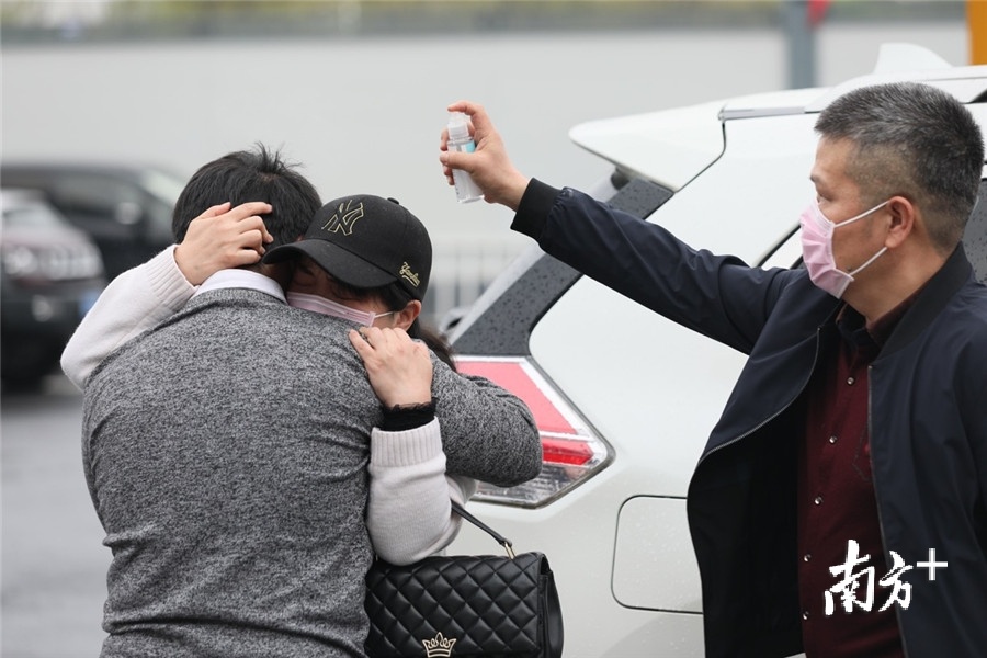 2020年3月24日，在武汉火车站，滞留外地两个多月后返汉的孟世奇与母亲相拥而泣，父亲在一旁向他们喷洒酒精。 刘宇 摄