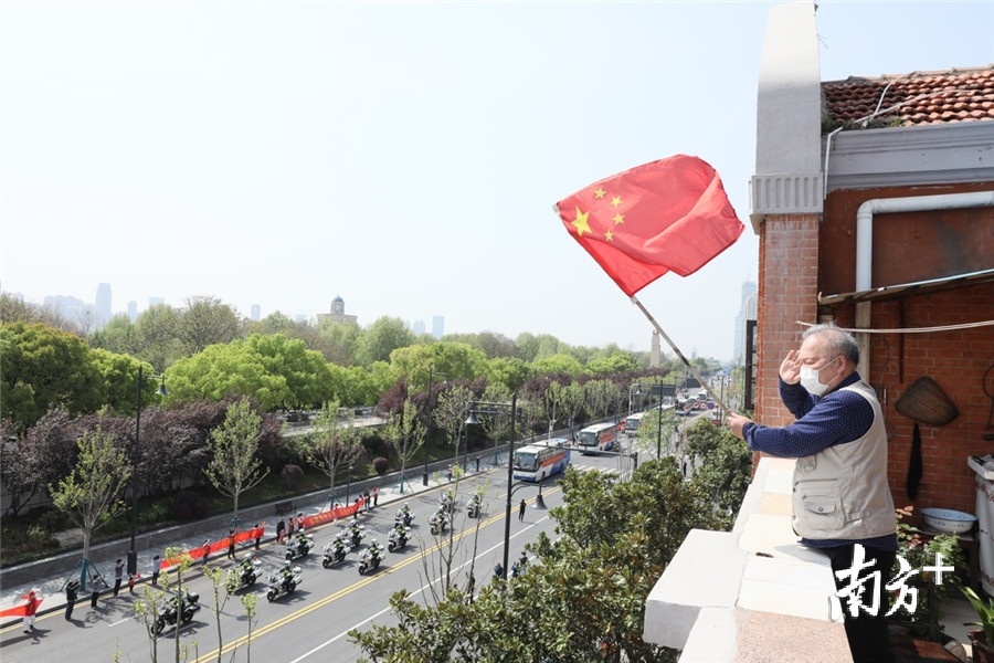 2020年4月7日，在汉口沿江大道旁的自家阳台上，65岁的退伍老兵王老伯向撤离武汉的北京医院援鄂国家医疗队的车队敬礼。刘宇 摄