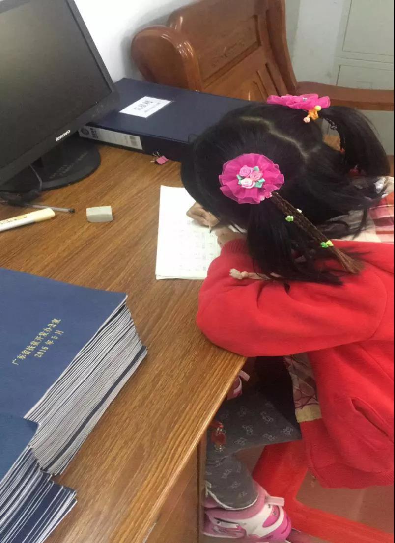 女儿在堆满贫困户帮扶记录簿的办公桌上认真学习。