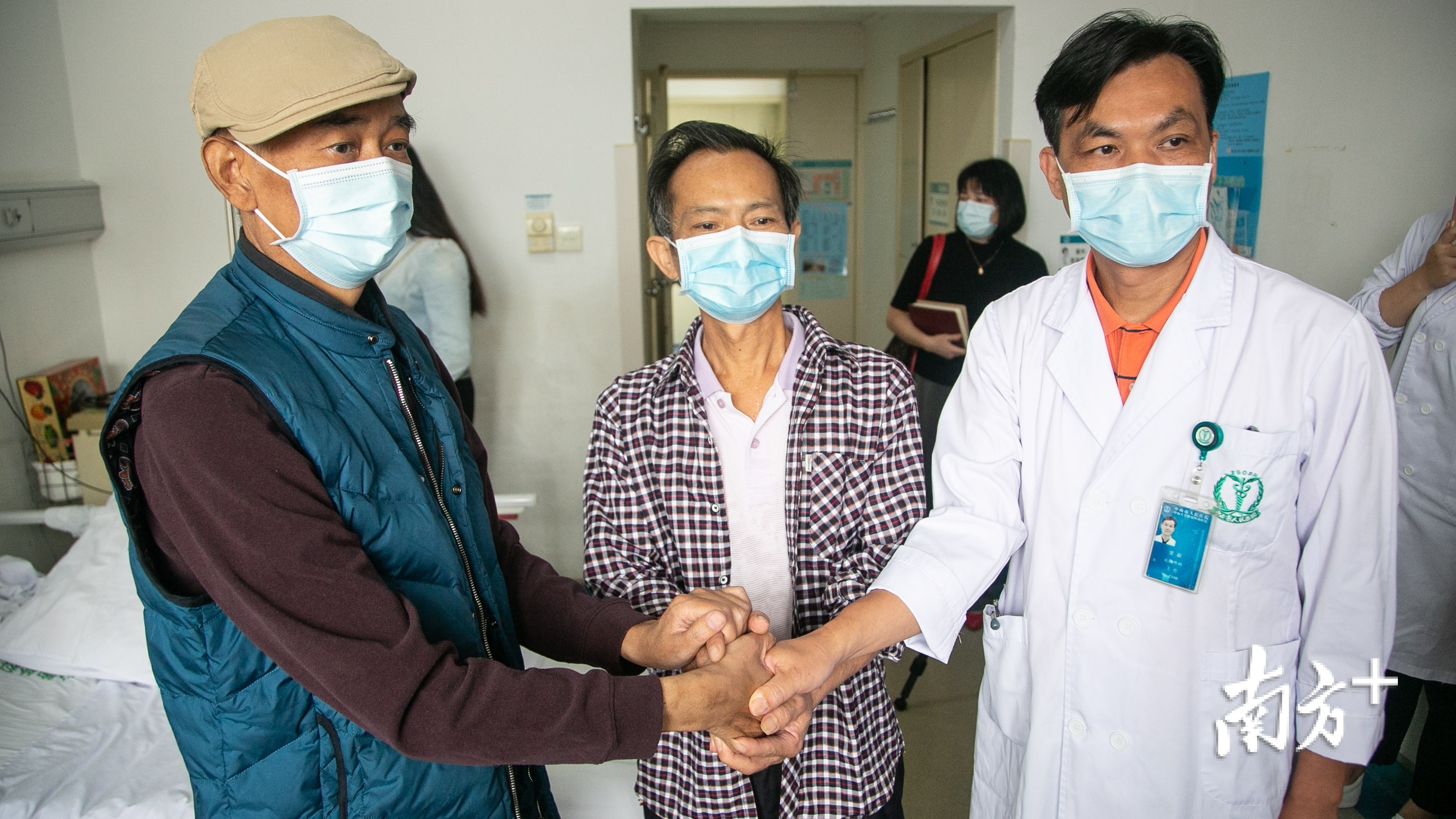 高先生、李先生、梁医生三人握手。