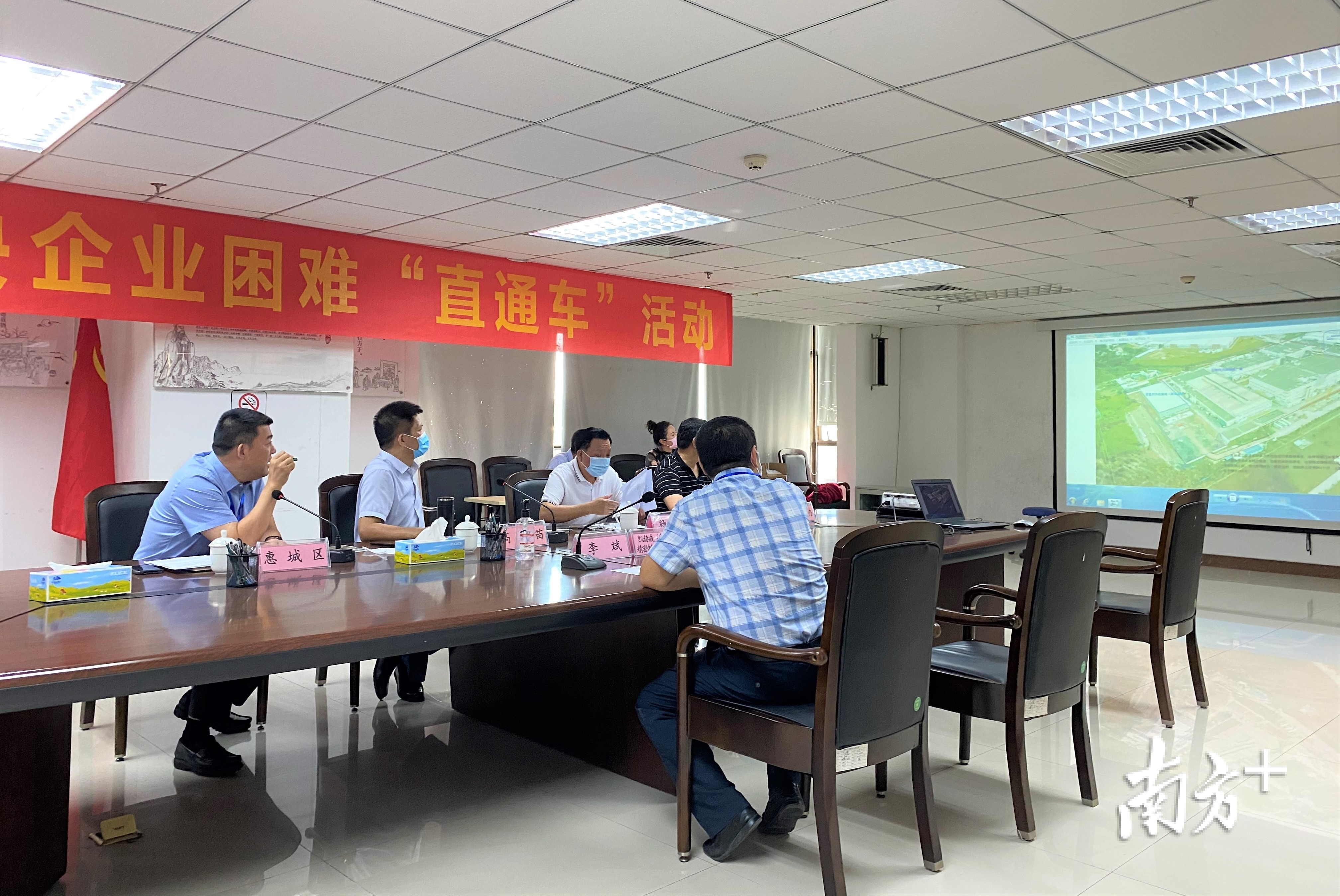 “直通车”活动现场，市领导与企业负责人观看投影研究解决问题。