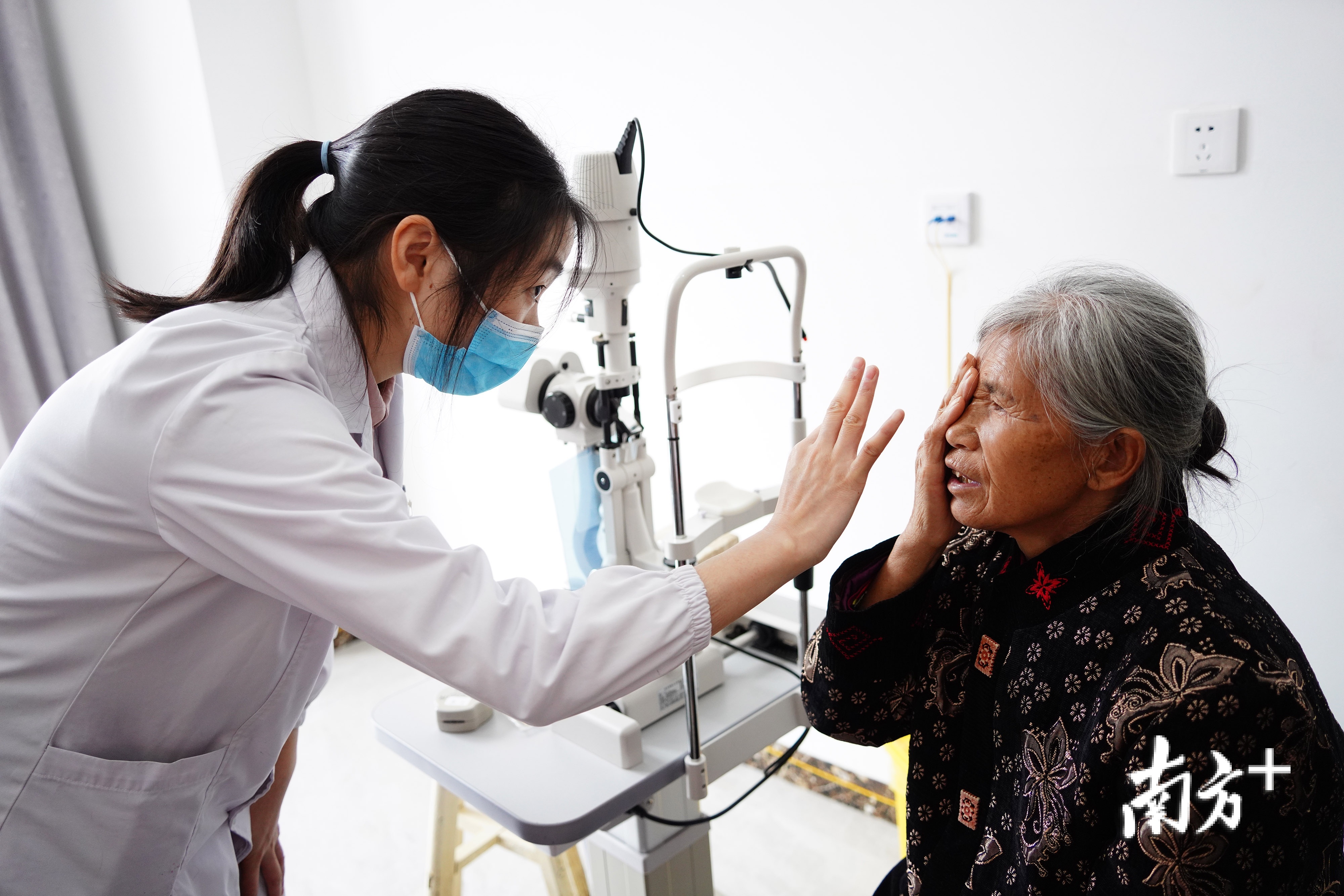 诊疗室内医生王黎正拿着手电筒为一位患者检测。