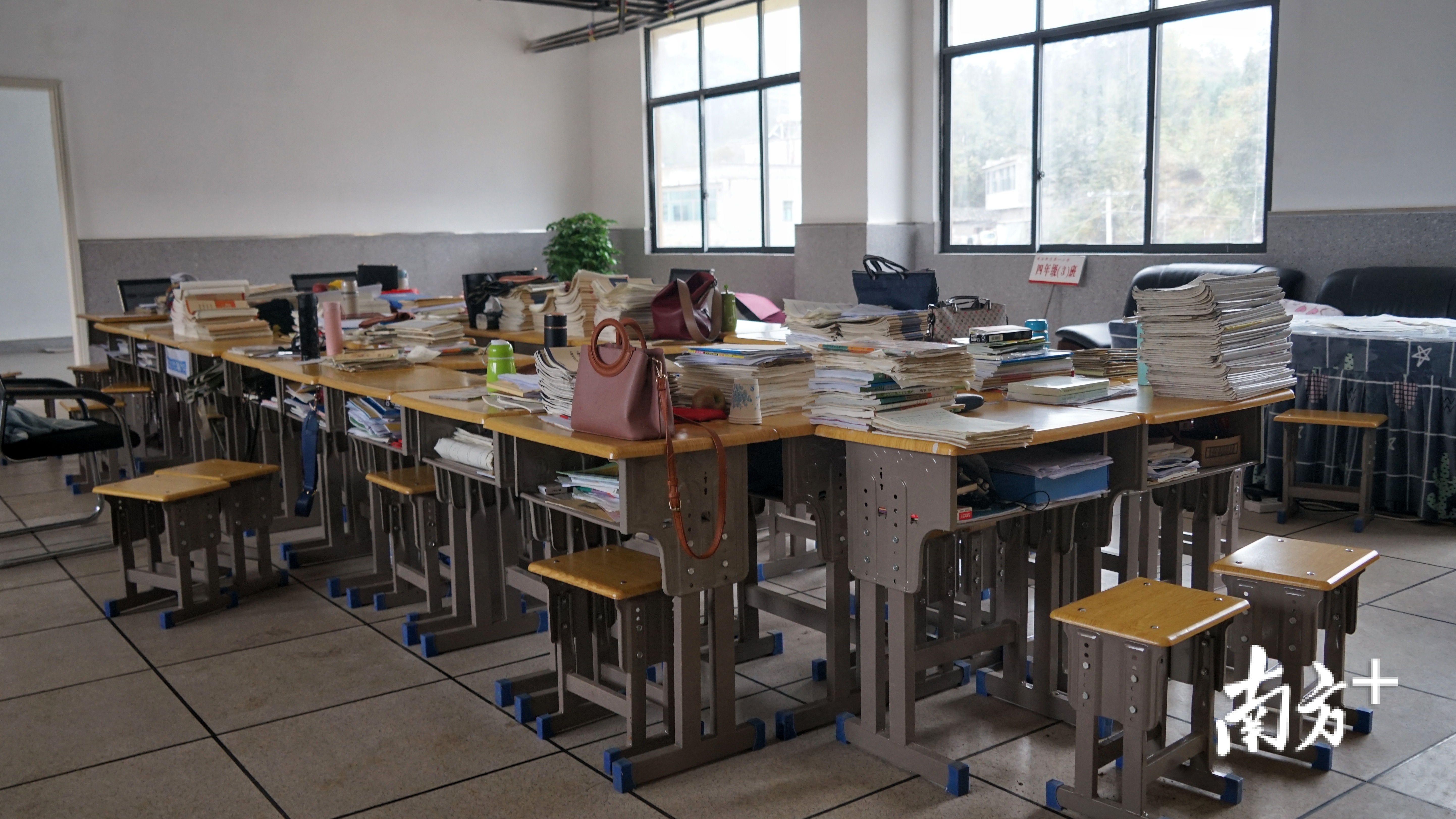 为了让学生使用的教室优先布置,教师办公室还来不及购置办公桌,只用学生书桌简易拼接。