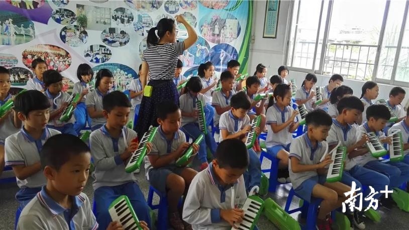沙头中心小学老师正在教育学生演奏乐器。