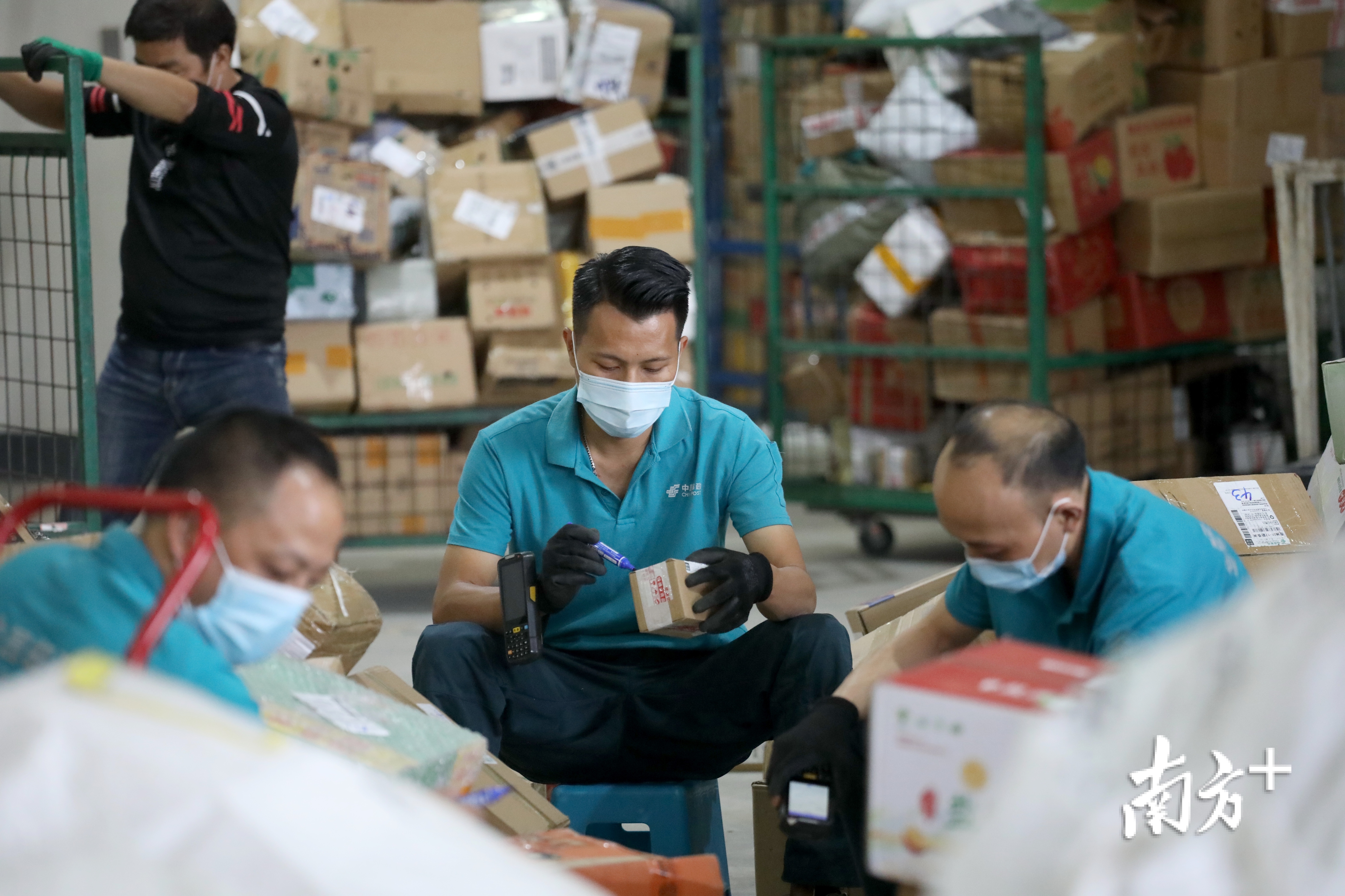 工人在对每一个包裹作标记,分类,他的身后全是装满包裹的手推车.