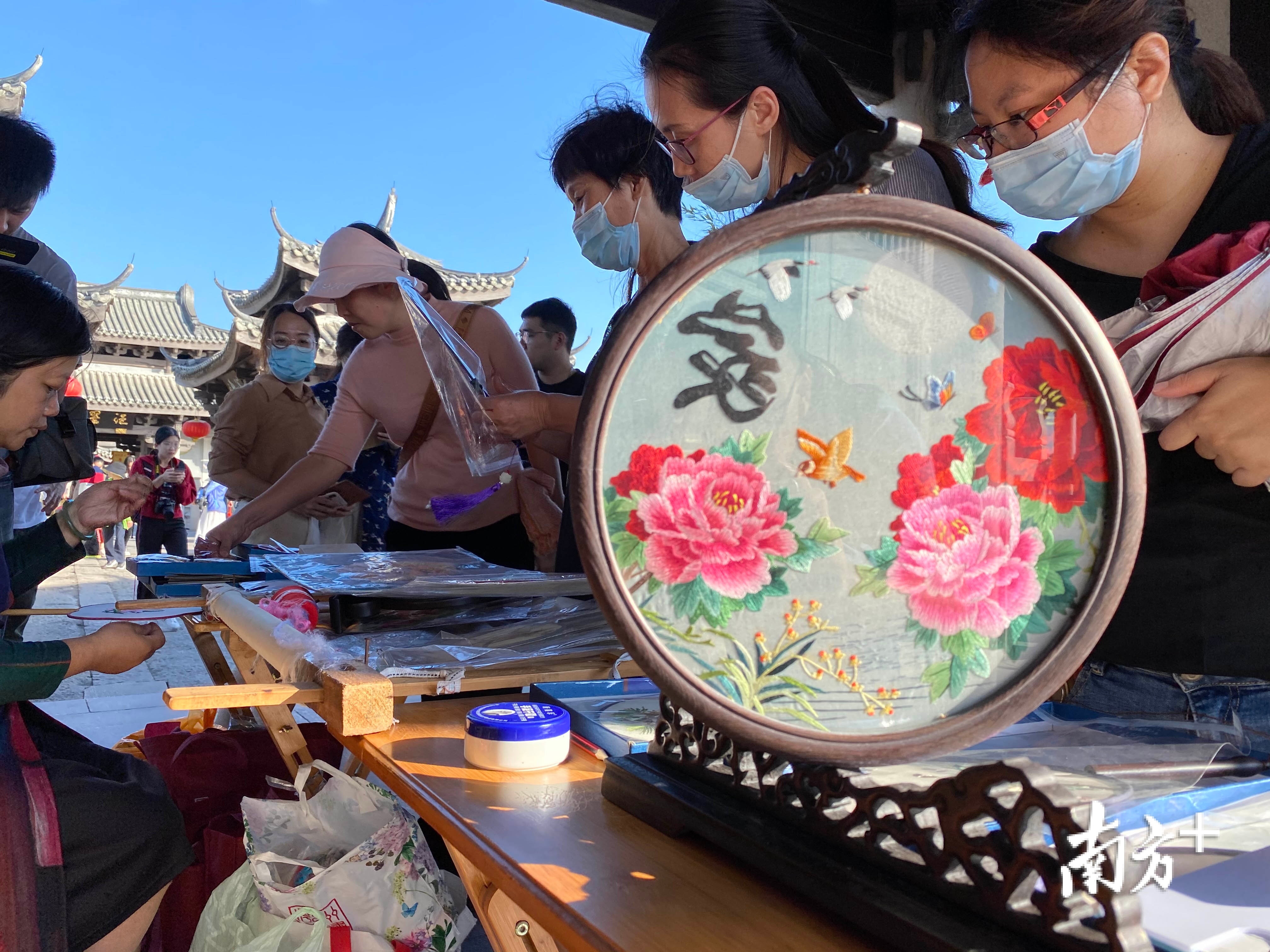 图为游客在广济桥上欣赏潮绣制作技艺。