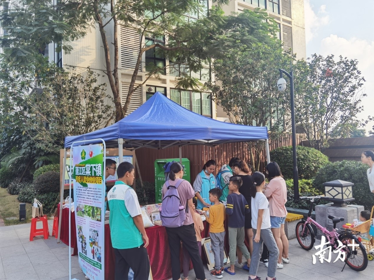 社工和残疾学员一起向居民介绍助残项目和手工产品