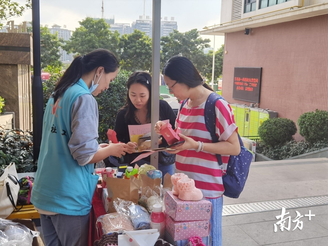 “蓝马甲”社工向居民介绍礼盒香皂和马赛克杯垫