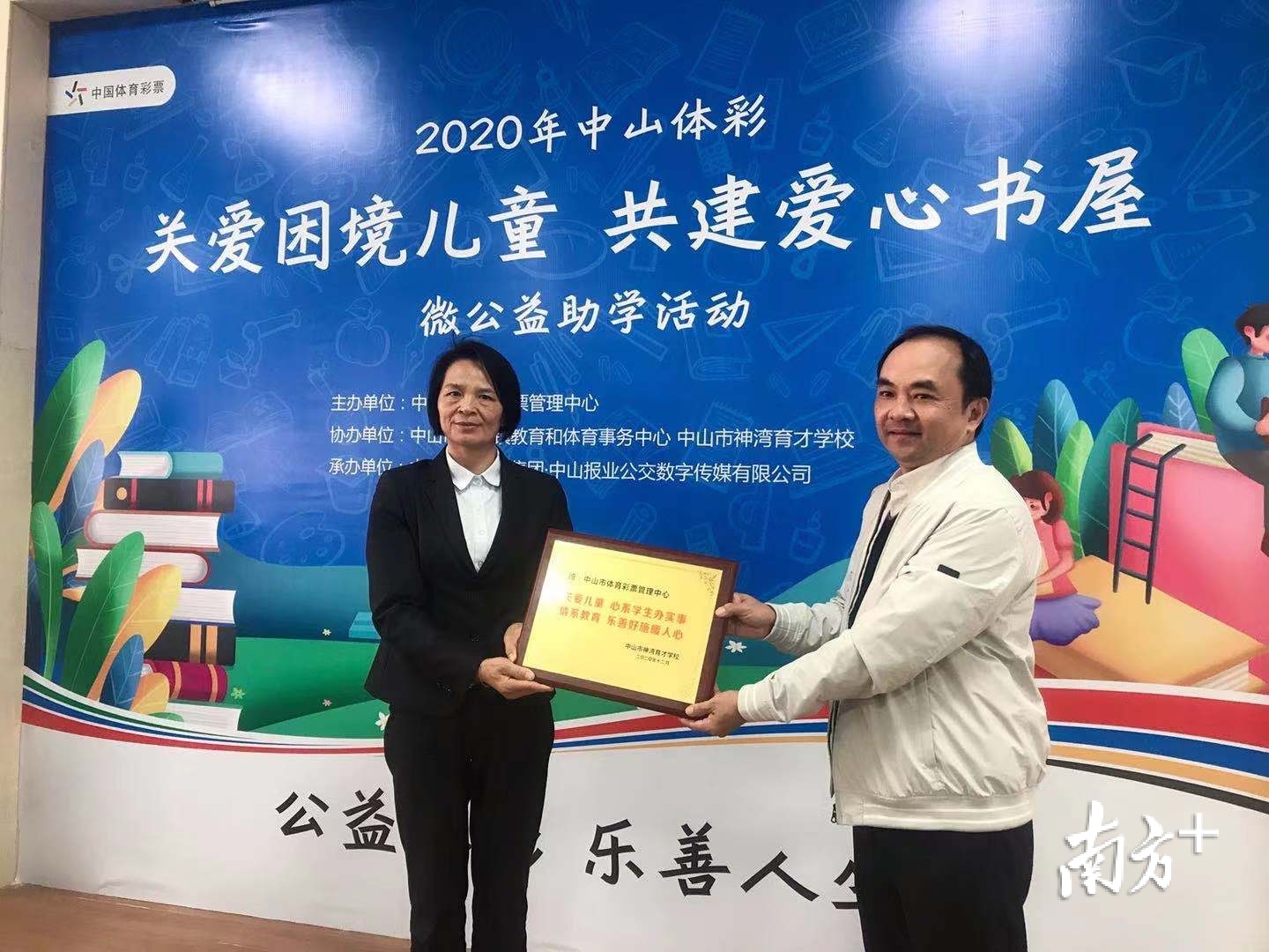 该校校长区焕珍向中山市体育彩票管理中心颁发感谢牌匾,张文建代表中心领牌。
